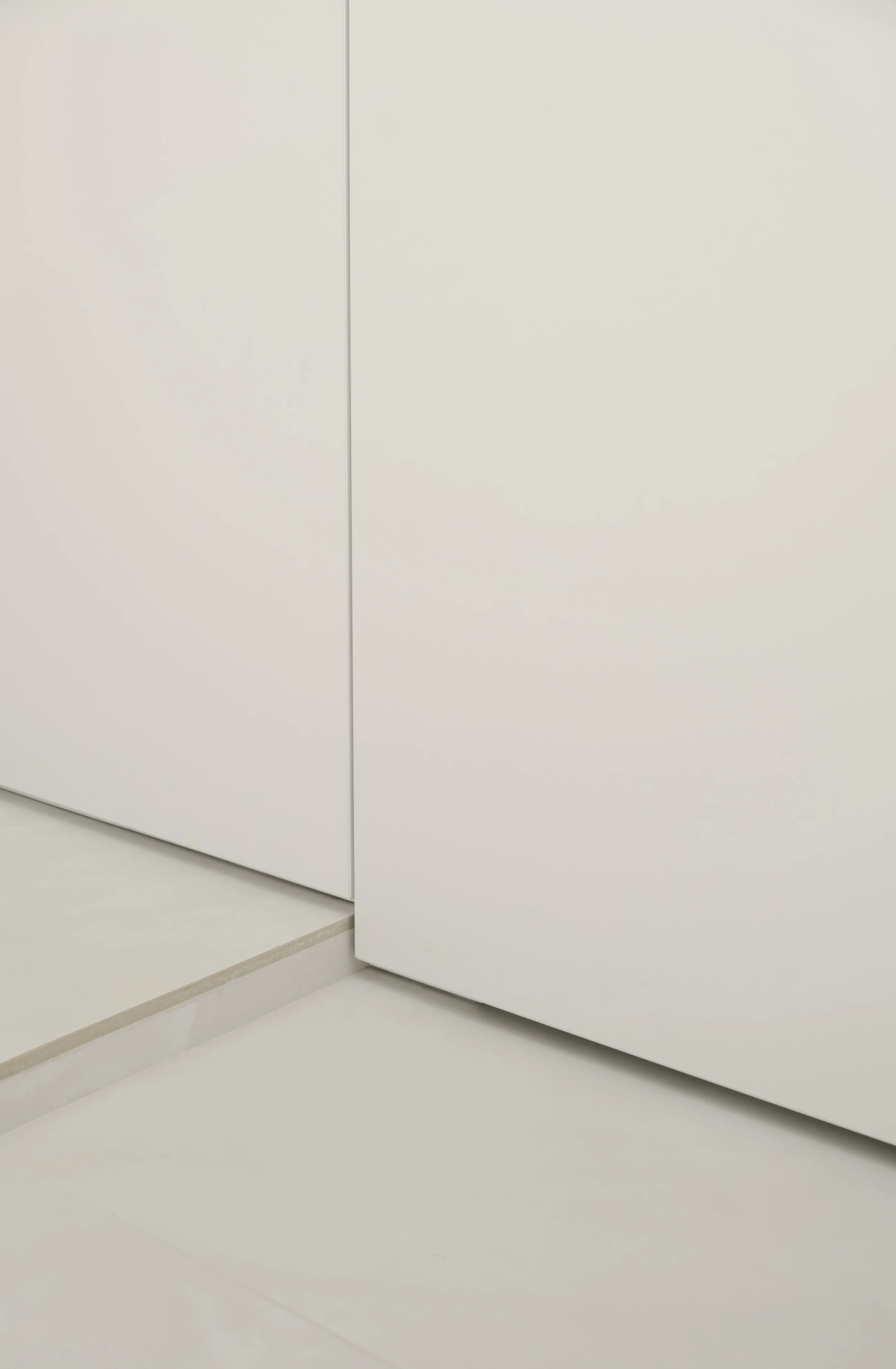 Minimalist white built-in cabinetry with clean lines and a seamless floor transition in a modern home interior.