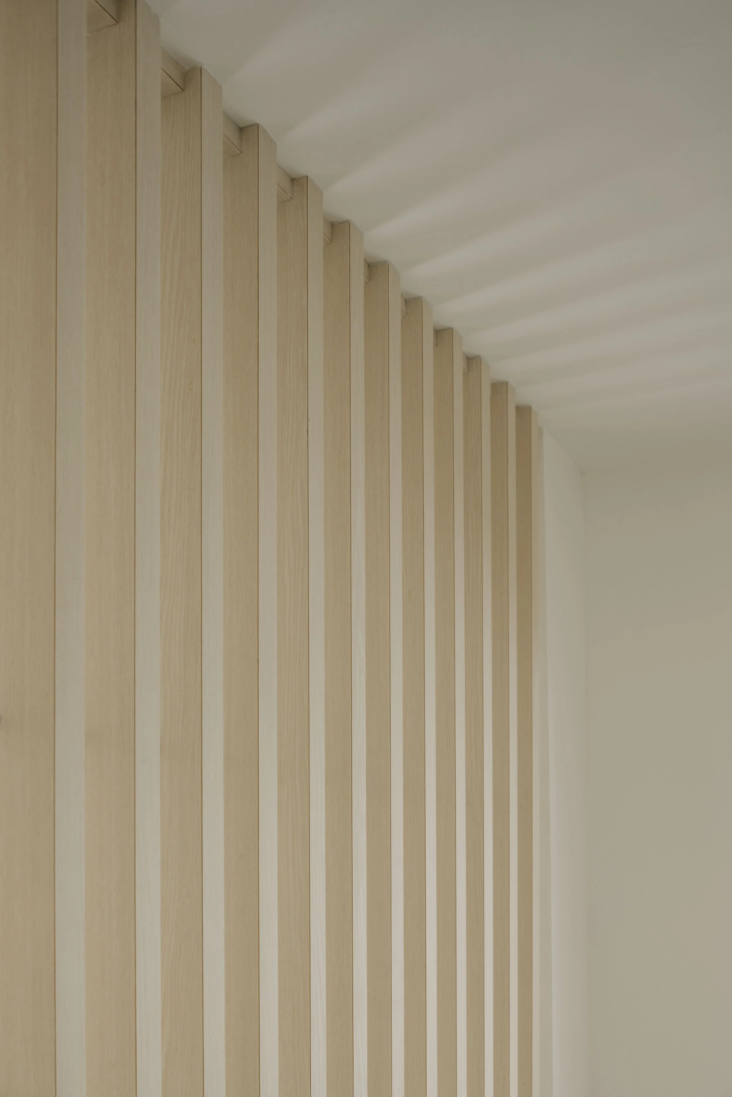Close-up of vertical light wood slat feature wall showcasing clean lines and premium minimalist carpentry workmanship.