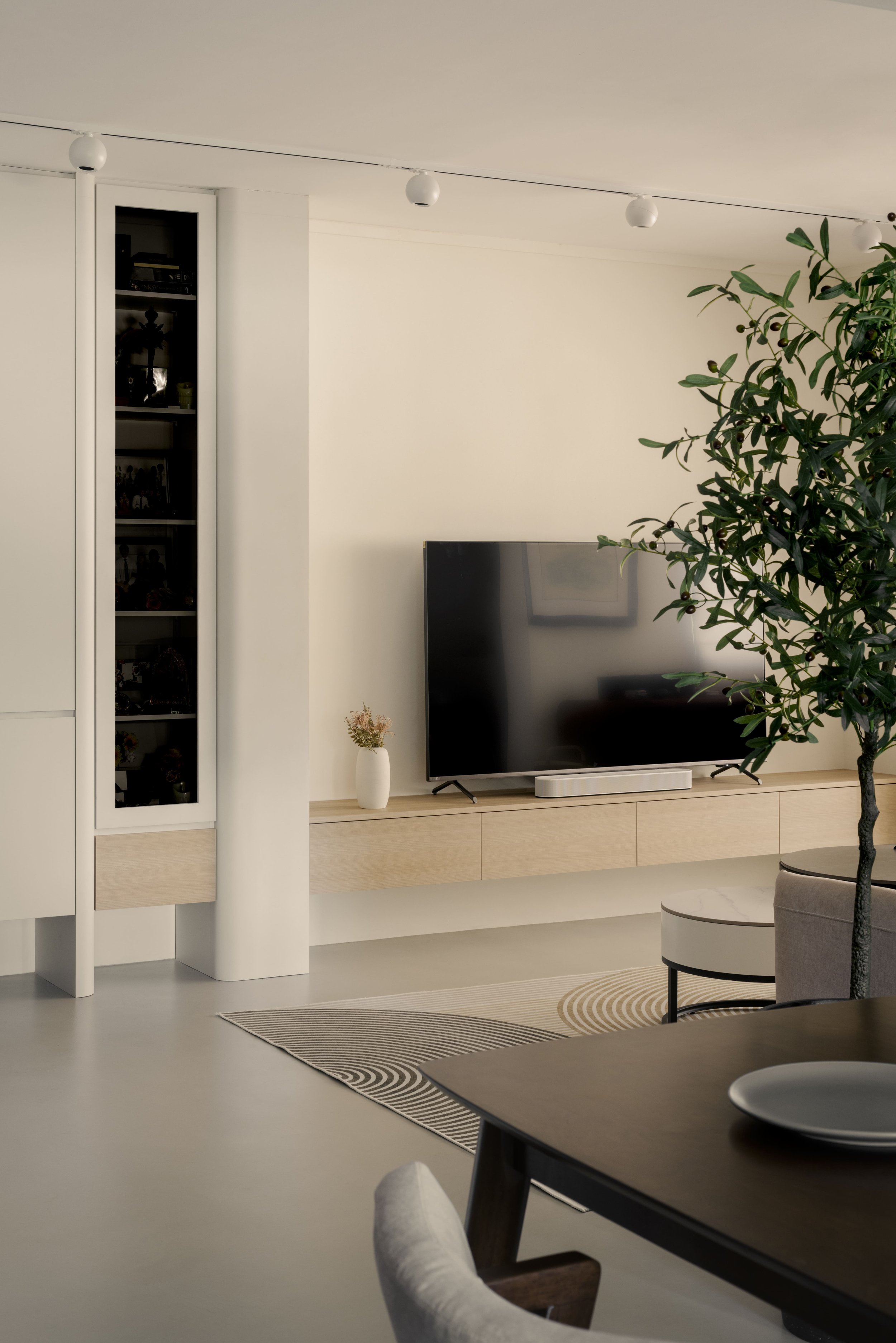 Modern living room with built-in TV console, display cabinet and light neutral finishes in a contemporary home interior.