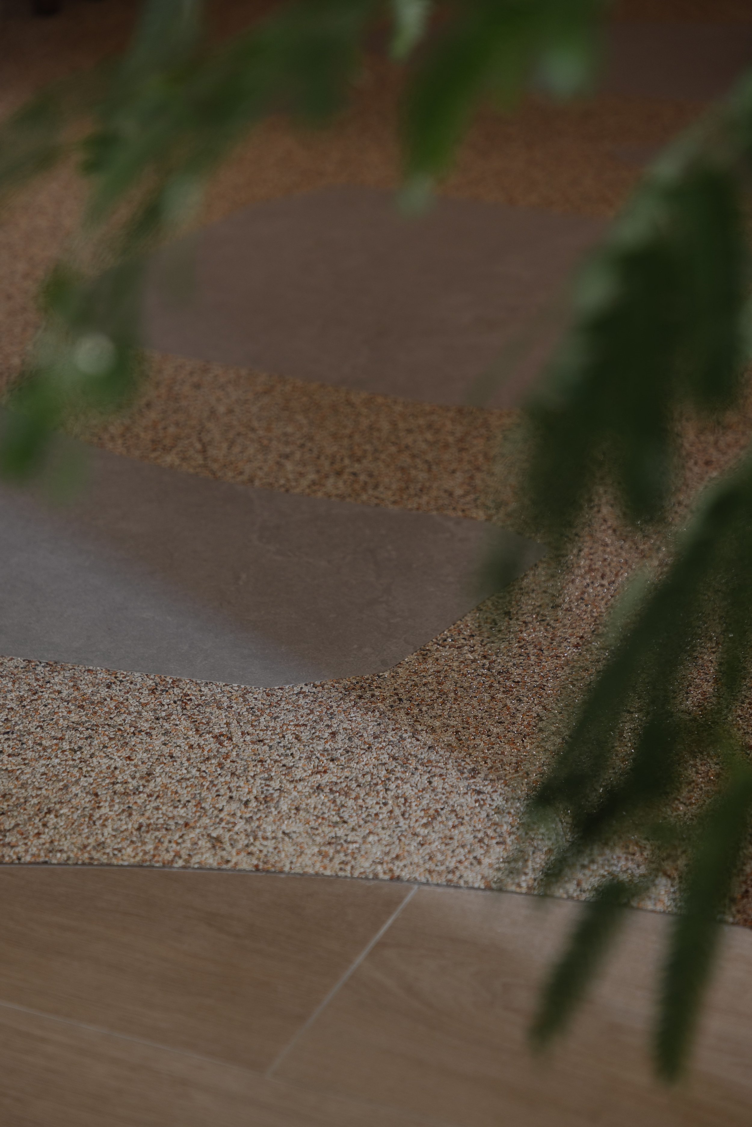 Close-up of textured flooring transition in a modern Singapore home, featuring epoxy pebble and wood tones with soft natural detailing.