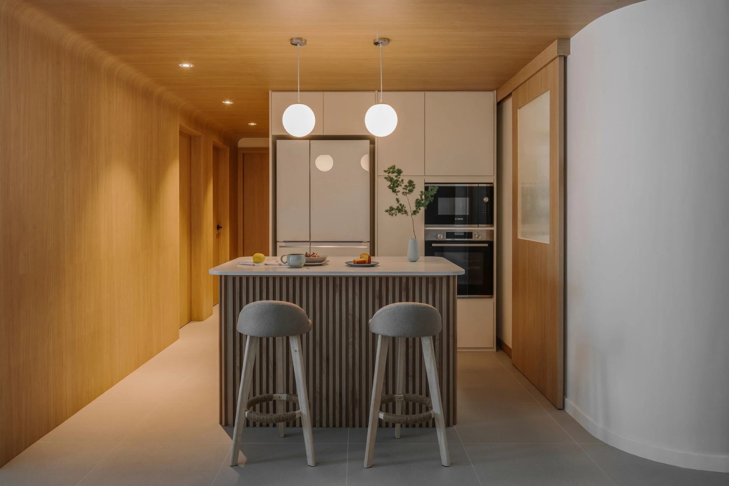 Modern pantry area with fluted island, curved timber ceiling, white cabinetry and pendant globe lights.