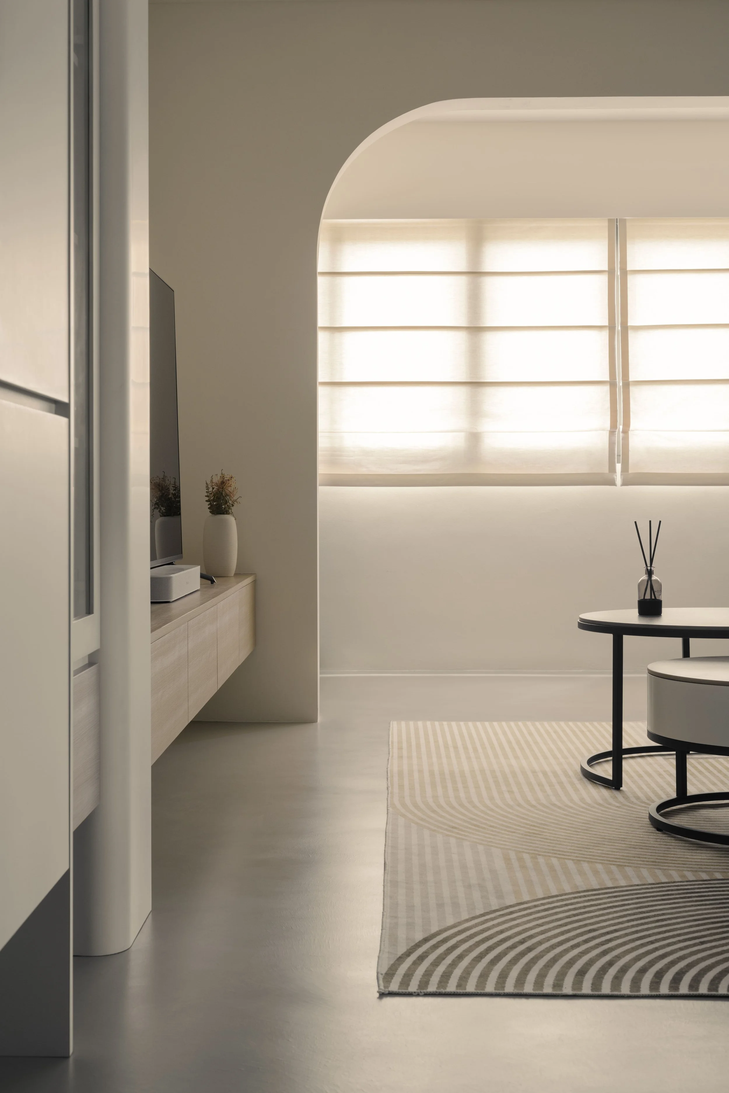 Minimalist living room with arched doorway, neutral palette and floating console in modern interior design by Lite Design Collaborative.
