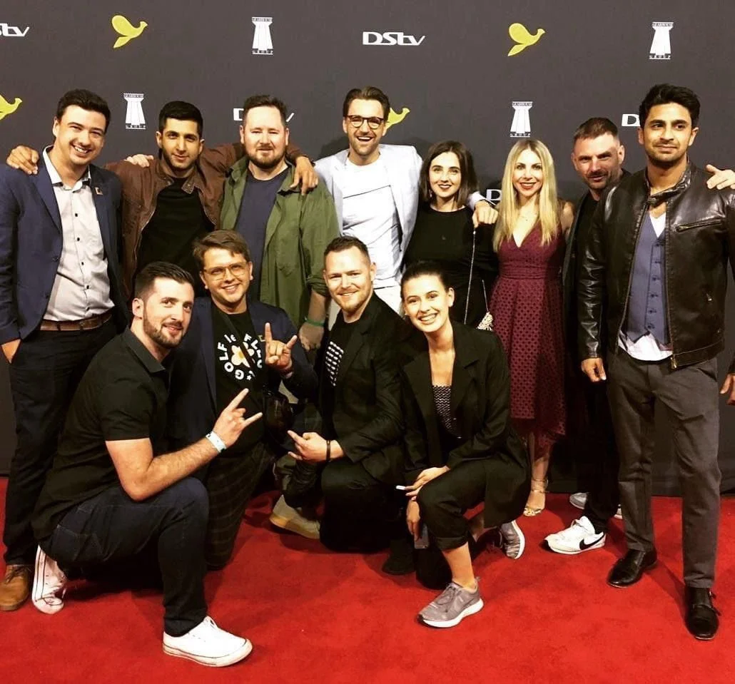Group of people posing on a red carpet at a media event