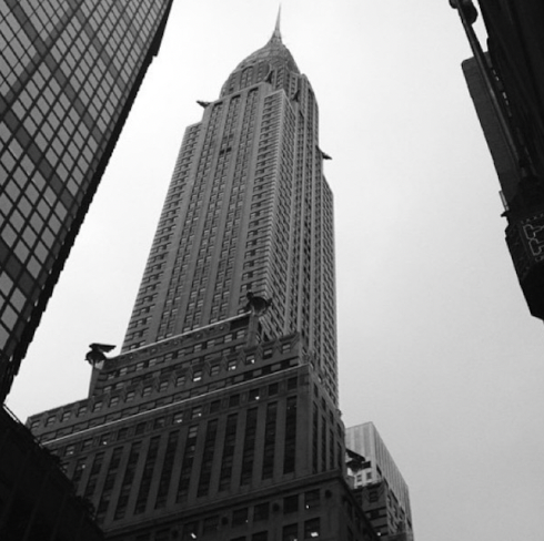 Black and white photo of the Empire State Building in New York City taken from street level.
