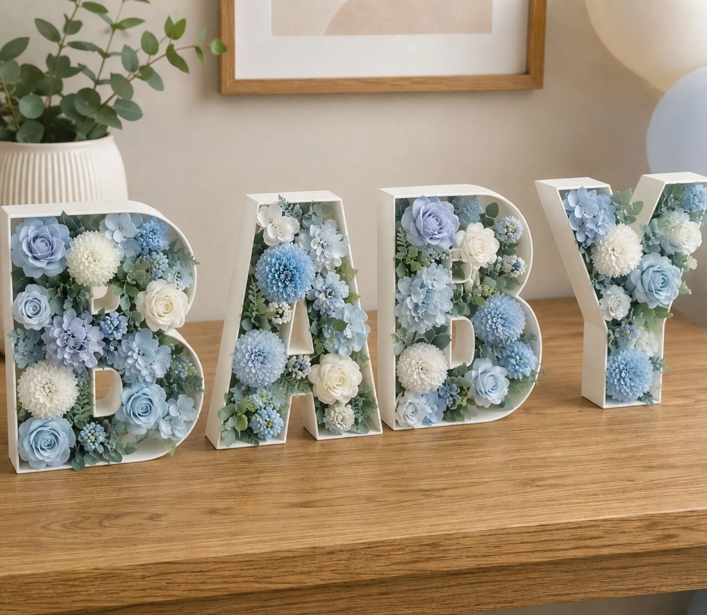 light blue and white floral display inside of the white letters spelling baby