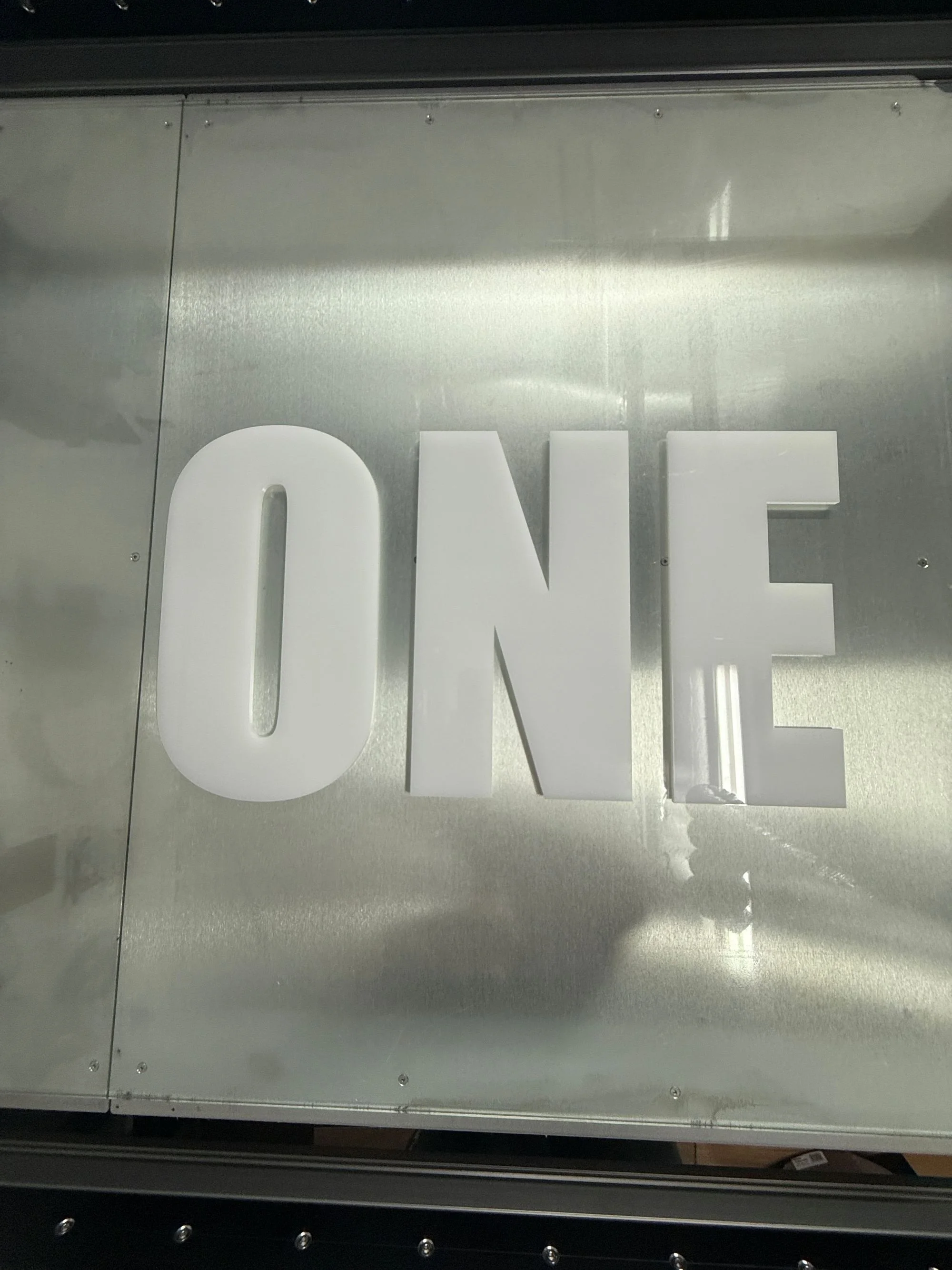 "ONE" 6mm opal acrylic letters sitting on a glass table