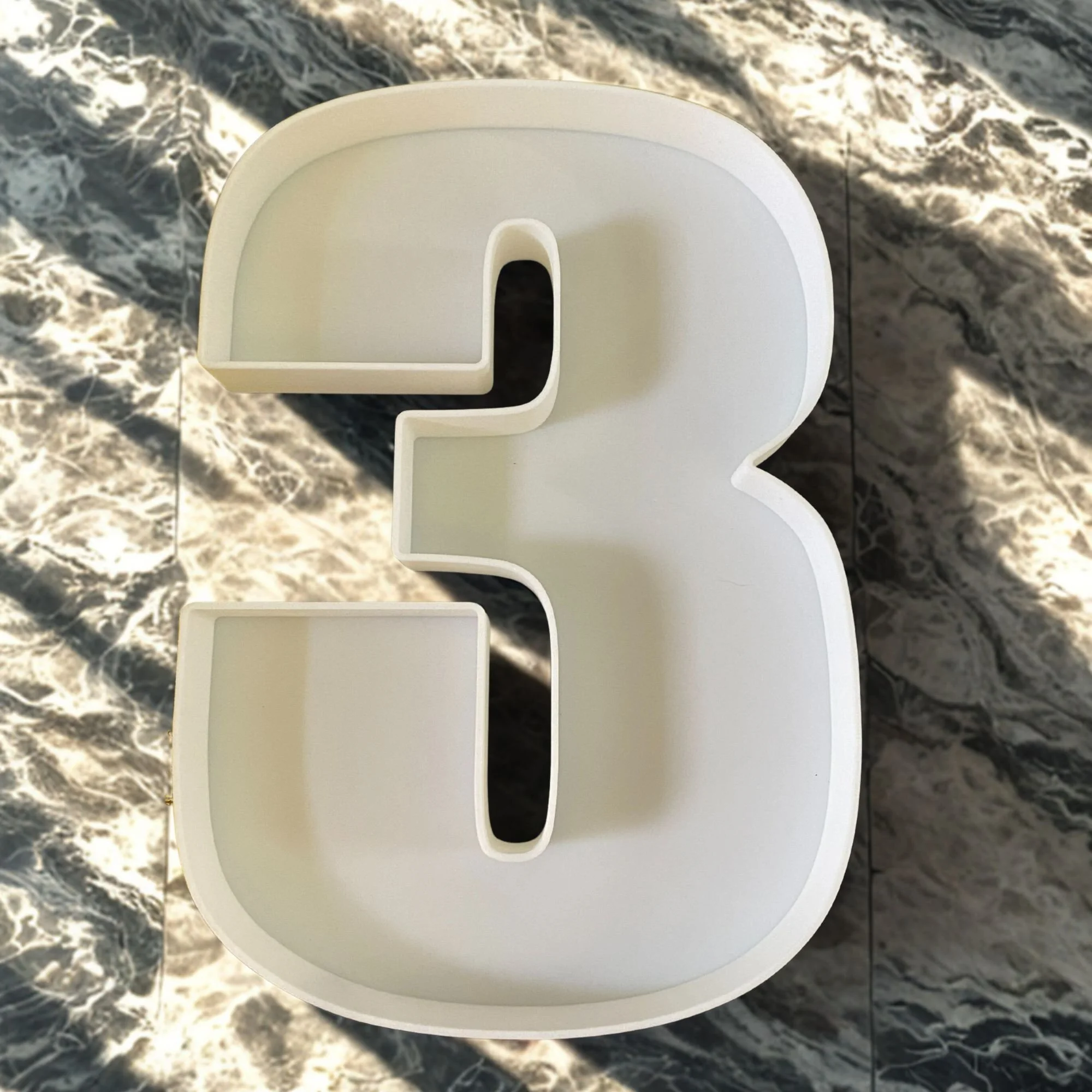 Plastic number 3 fillable letter on a marble table