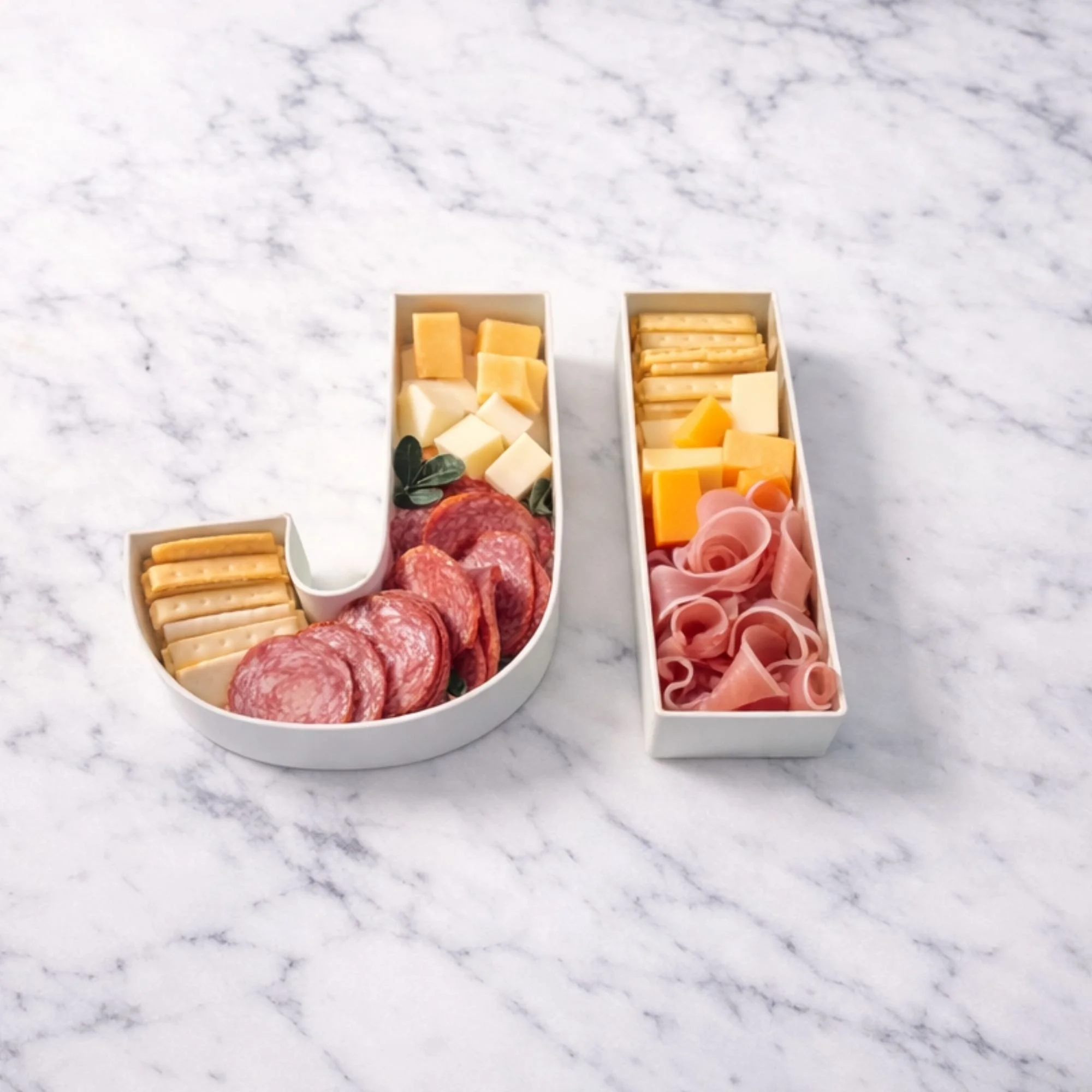 Marble table with letters JI full of salami, cheeses, ham and biscuits