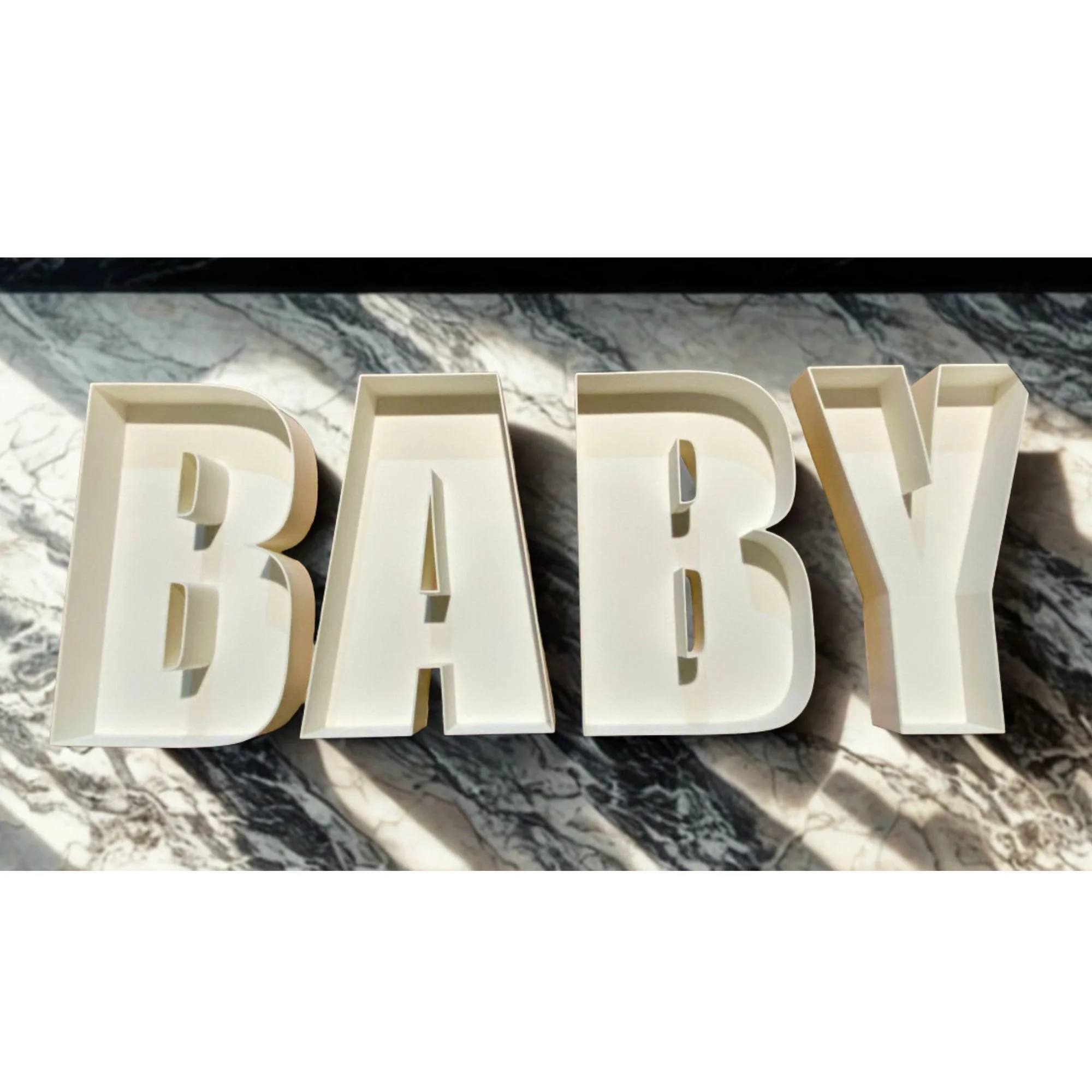 Baby is spelt out in white fillable letters on a marble table