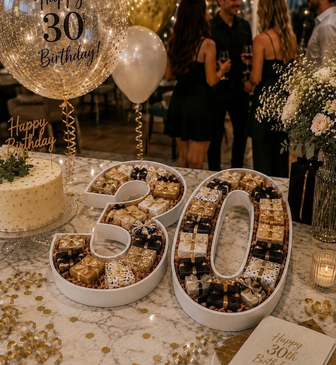 A 30th birthday celebration table decorated with a white platter number tray, gold balloons, and  a large 30-shaped food tray filled with small, wrapped gifts.
