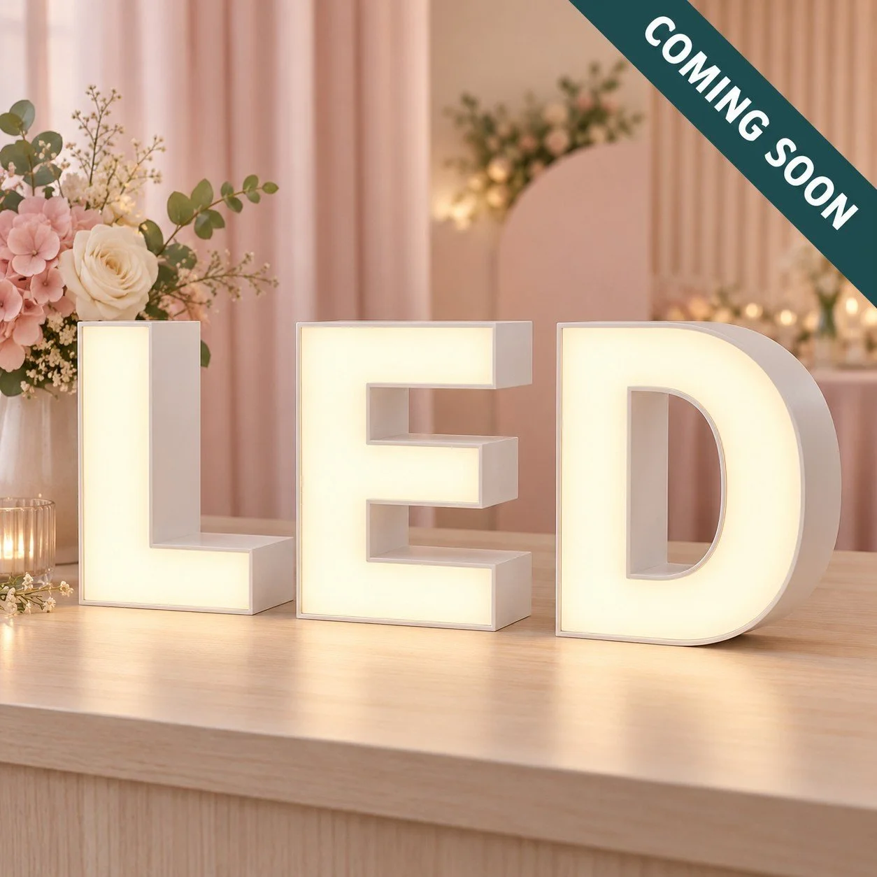 Illuminated decorative letters spelling 'LED' on a wooden surface with floral arrangements and a softly lit background, with a 'Coming Soon' banner in the top right corner.