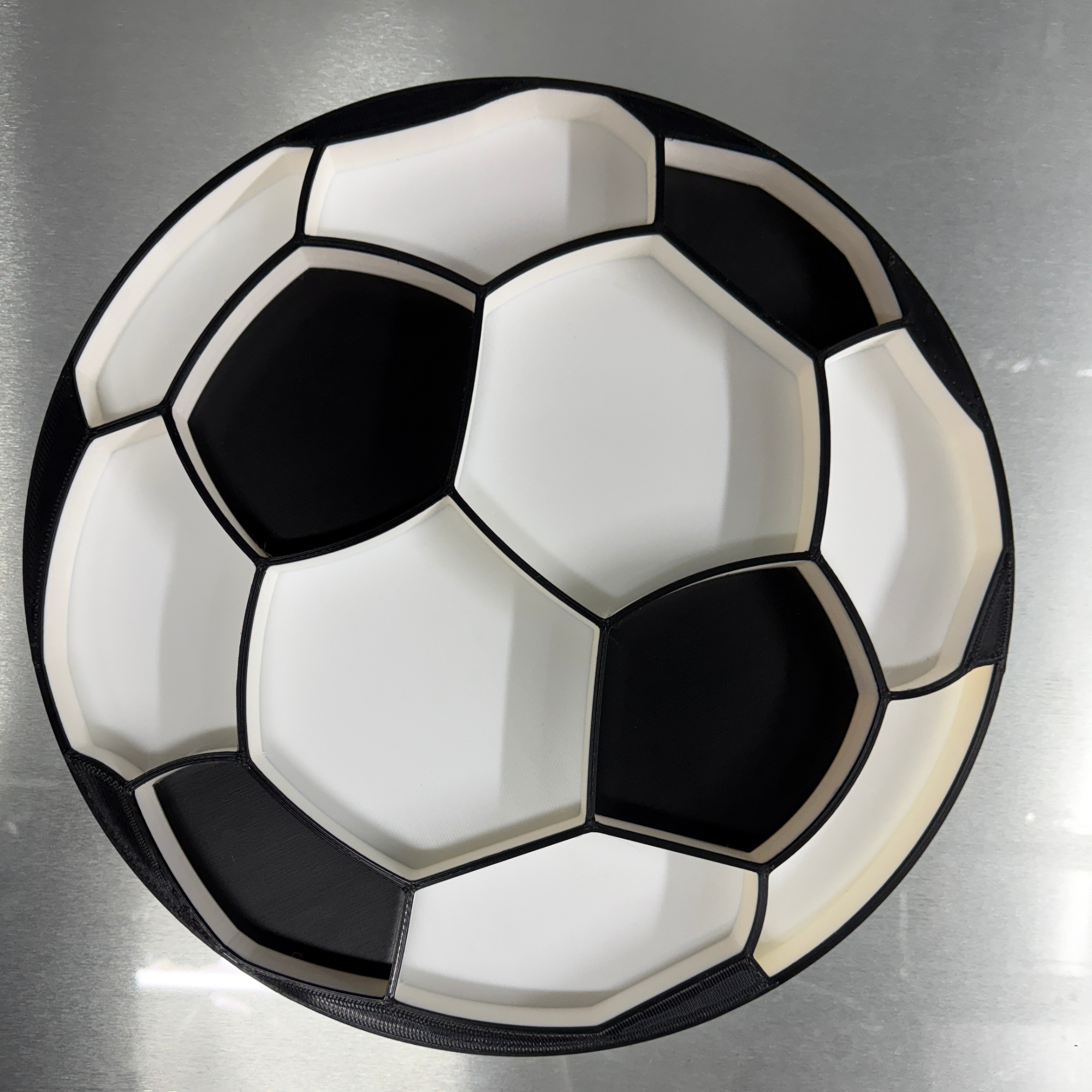 Food plate in the shape of a soccer ball sitting on a glass table