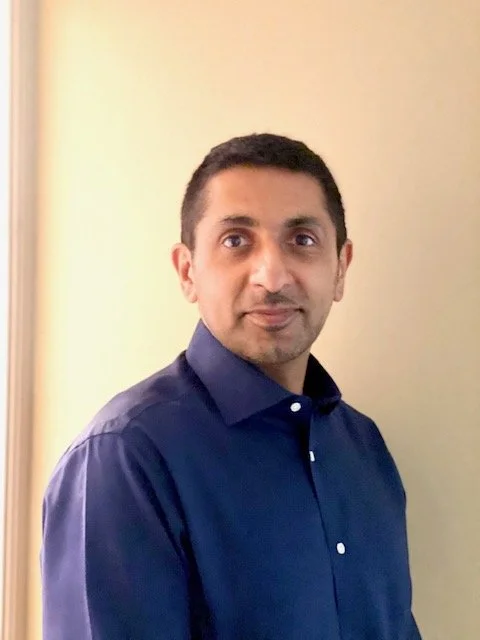 Asim Suleman in a shirt, smiling at the camera.