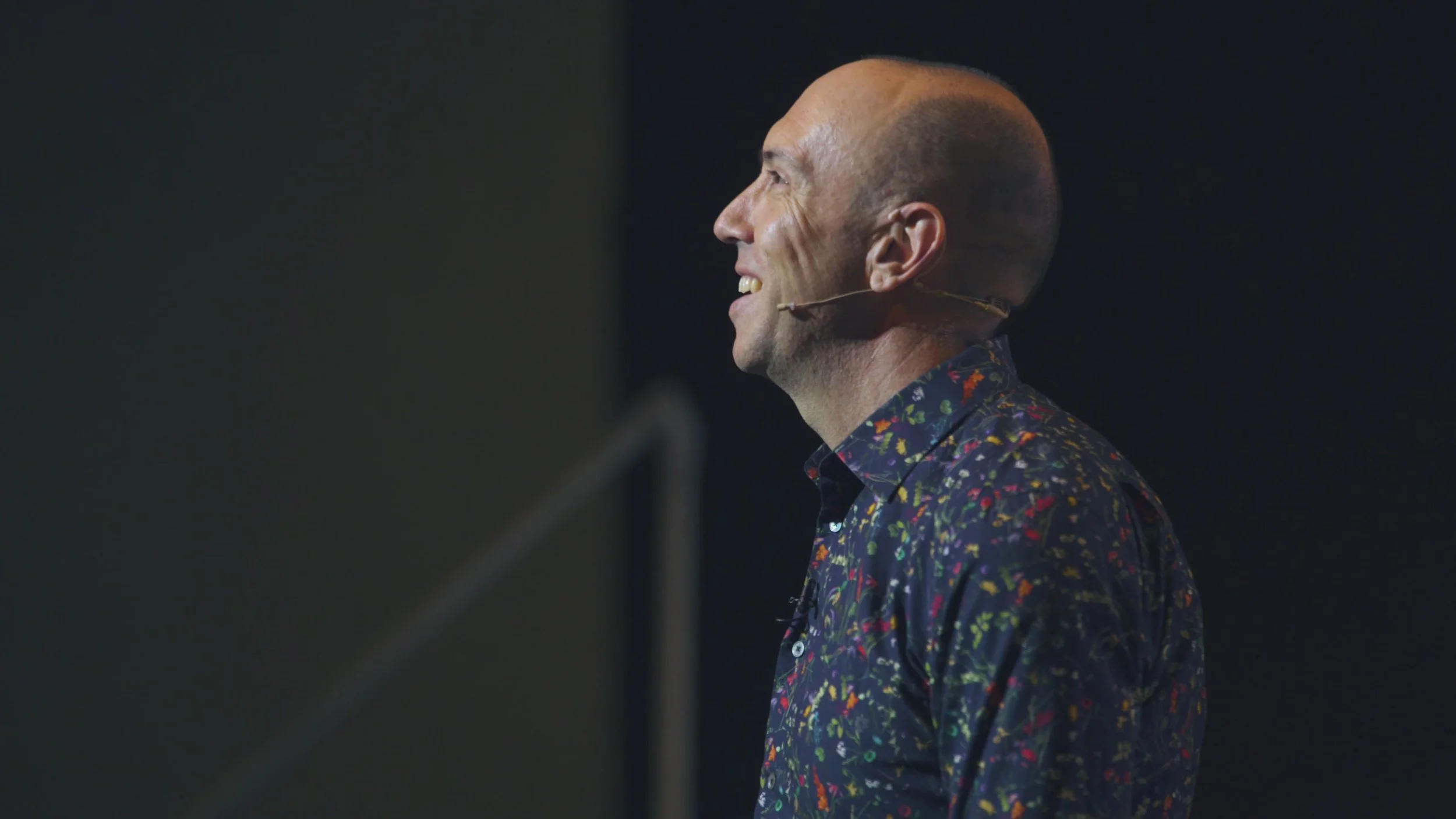 Professor Lorimer Moseley AO with a microphone, smiling.