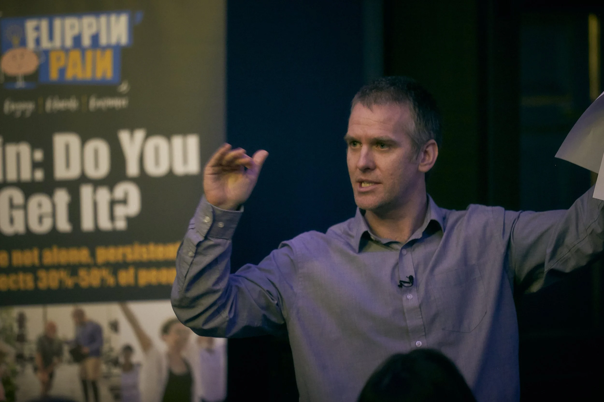 Professor Cormac Ryan speaking in front of a Flippin' Pain banner.