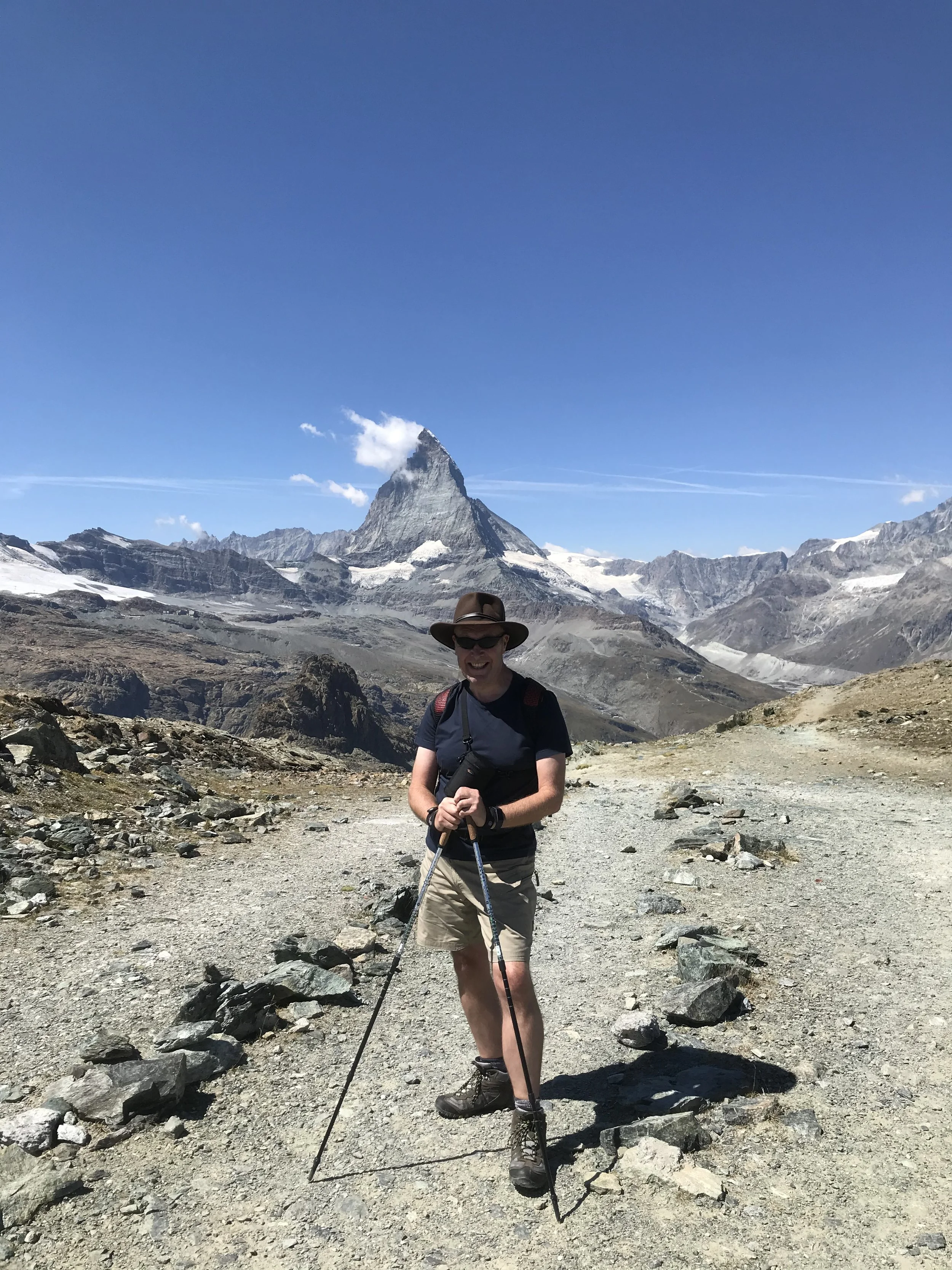 Ivor stood in a mountain range with hiking sticks.