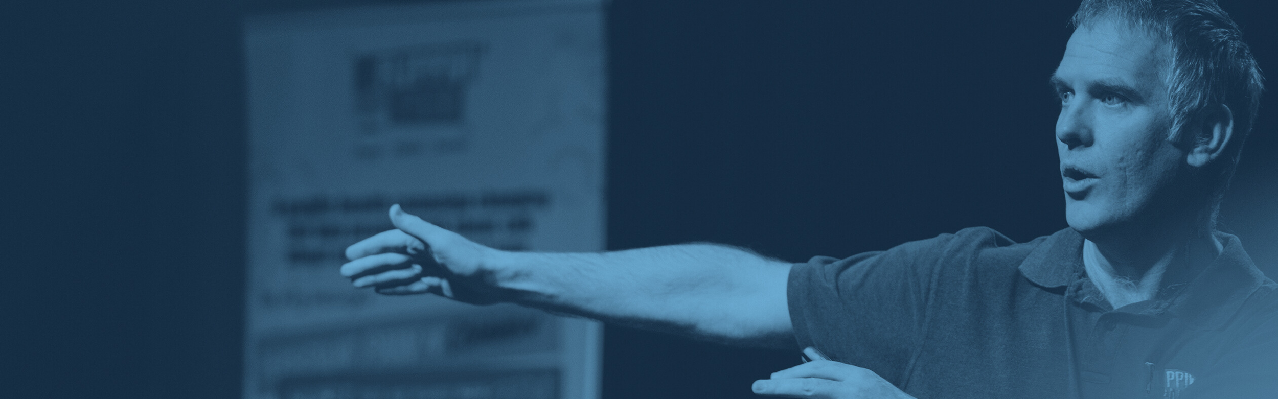 Speaker Cormac Ryan speaking and pointing left.