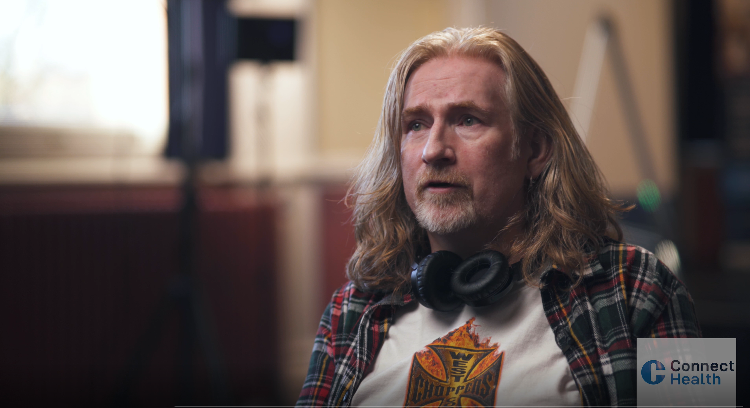 Brian with headphones around his neck, talking to the camera.