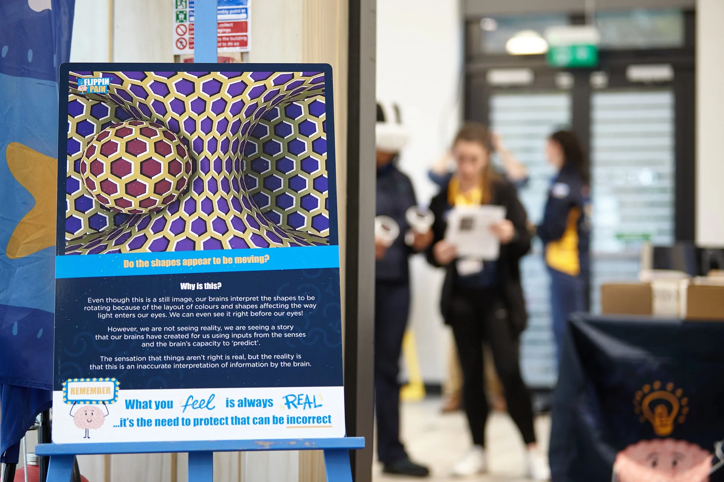 A metal sign with a visual illusion displayed on there.