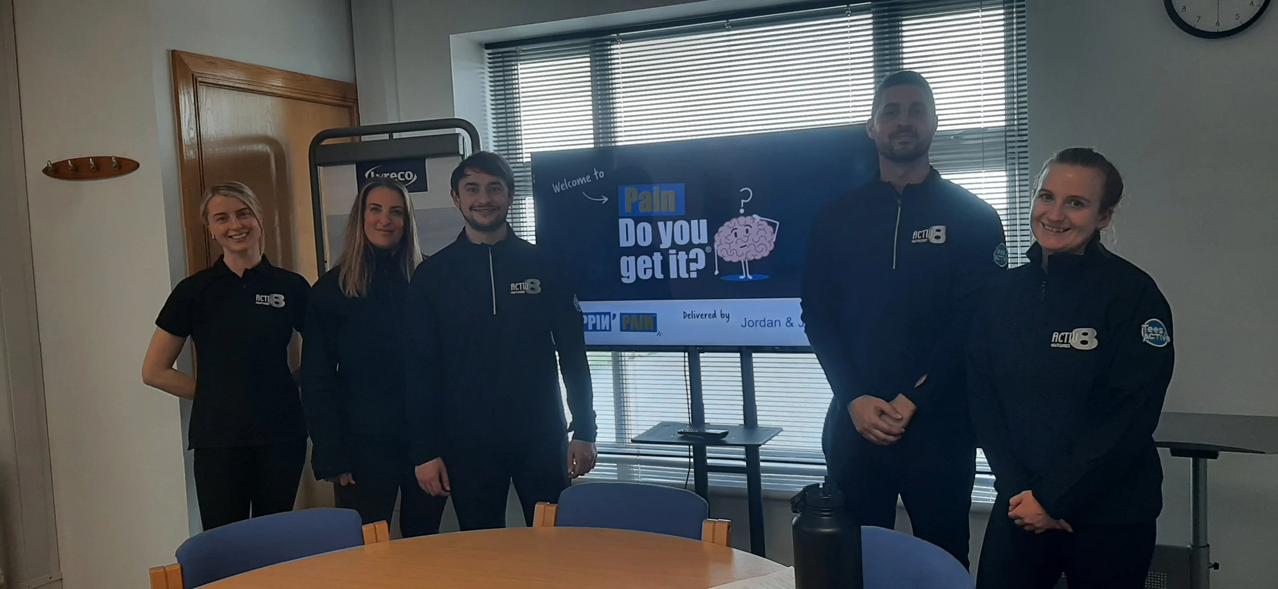A group of Painfluencers standing in front of a screen, having done a presentation.