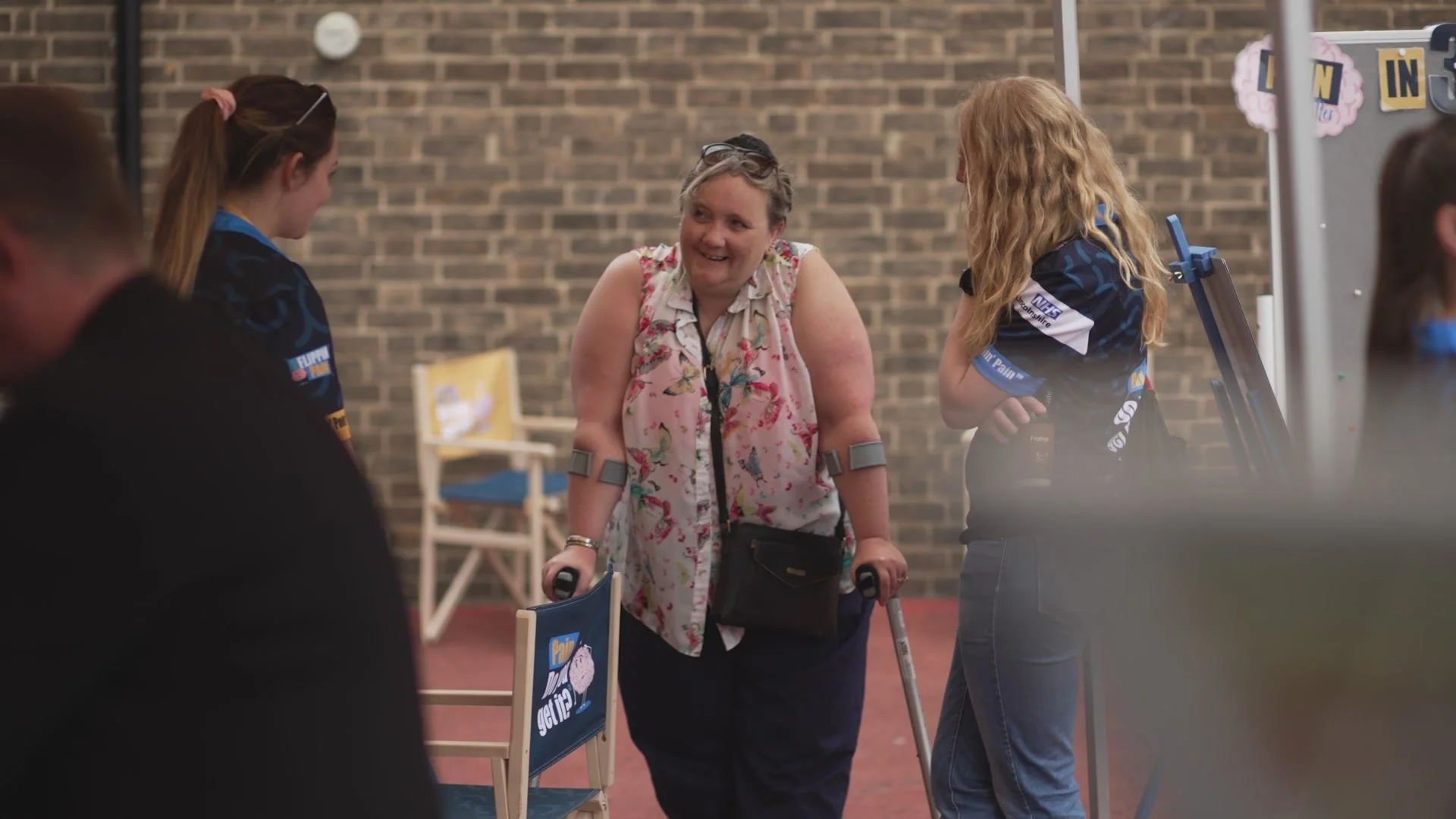 A photograph of a lady on crutches speaking to members of the Flippin' Pain team.