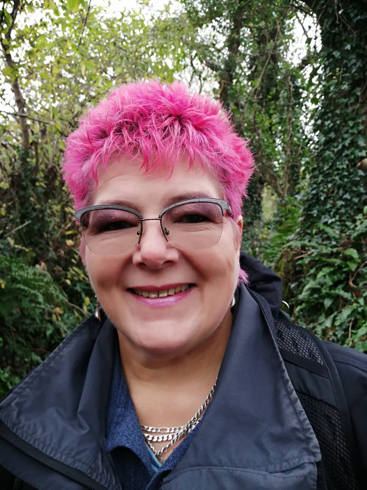 Louise in the woods, smiling at the camera.