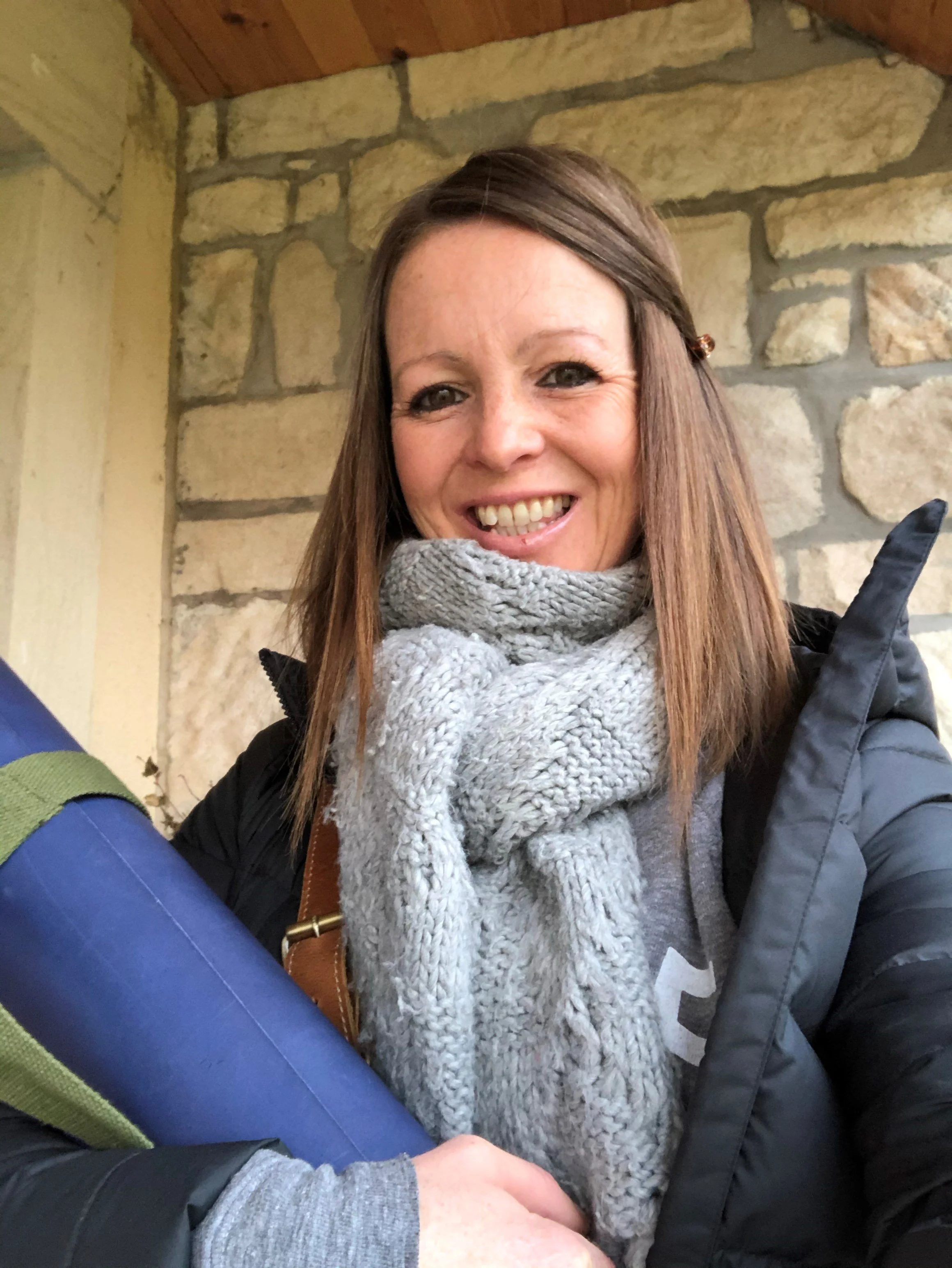 Ruth holding a yoga mat, smiling at the camera.