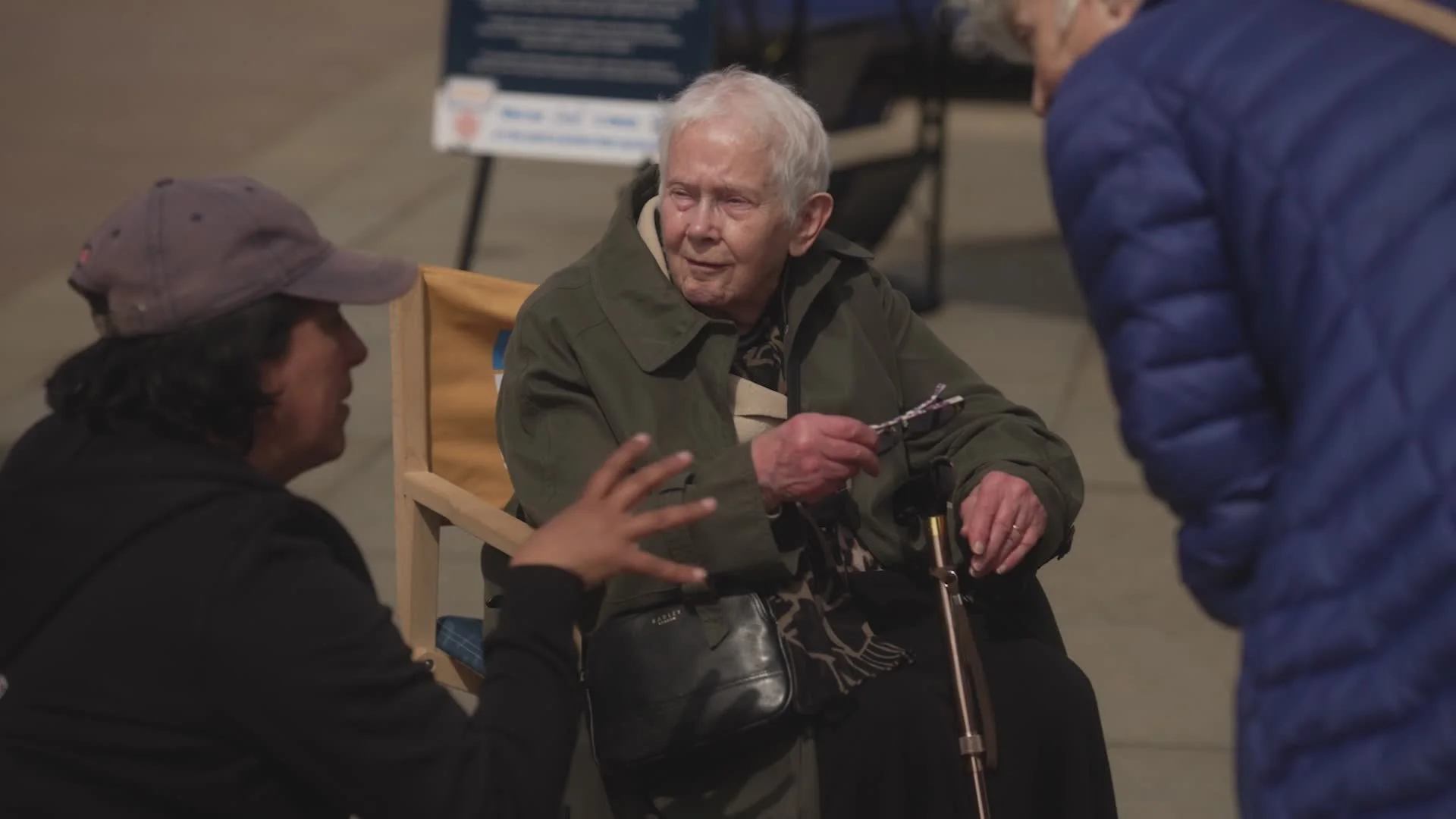 An elderly person with a walking stick listening to a Flippin' Pain team member chat to them.