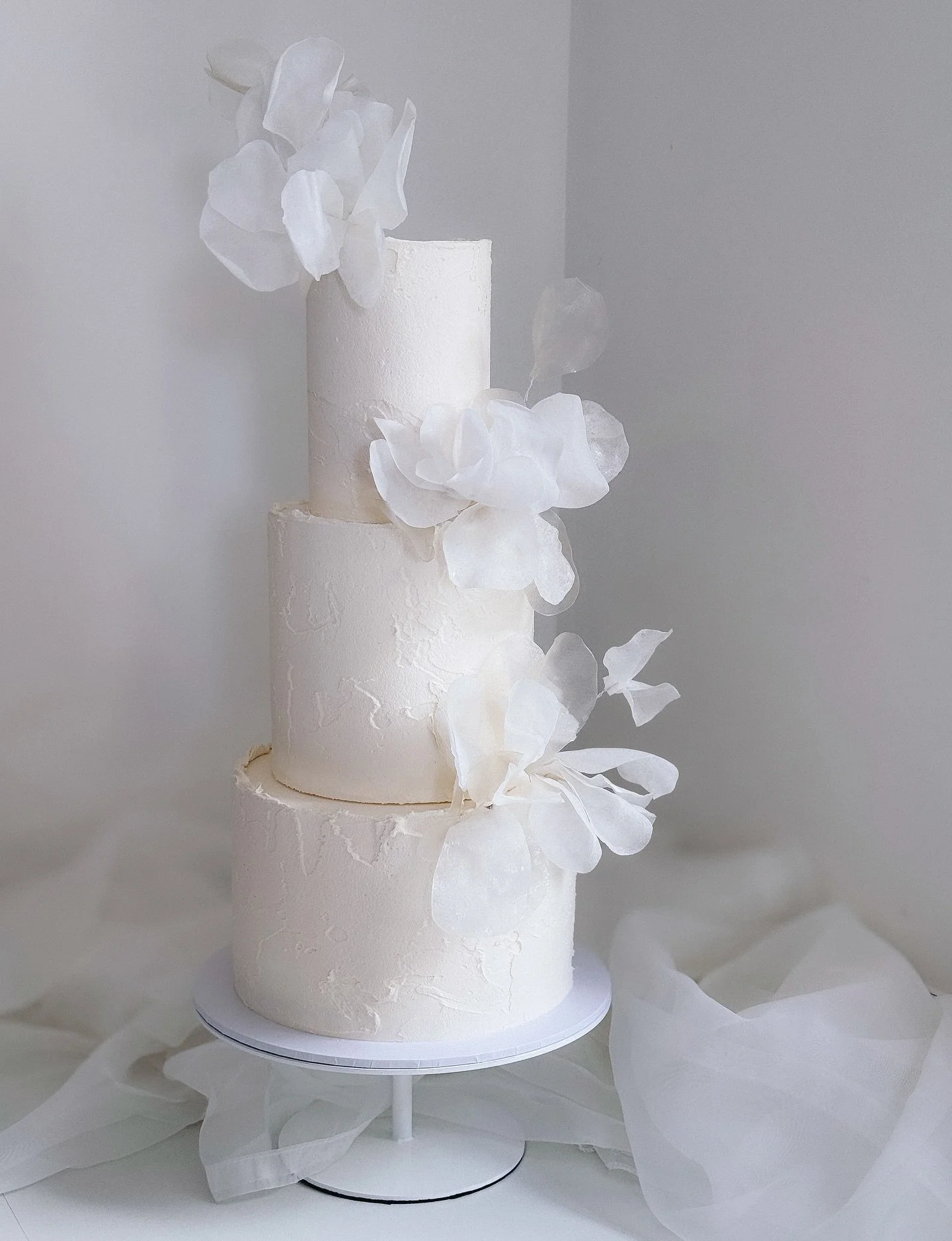Elegant, modern &amp; timeless 🤍
 A three tier wedding cake with buttercream textures and dressed with wafer paper florals giving a soft and romantic styling.  Designed to be a focal point for your special day.

#modernweddingcake #weddingcake #wafe