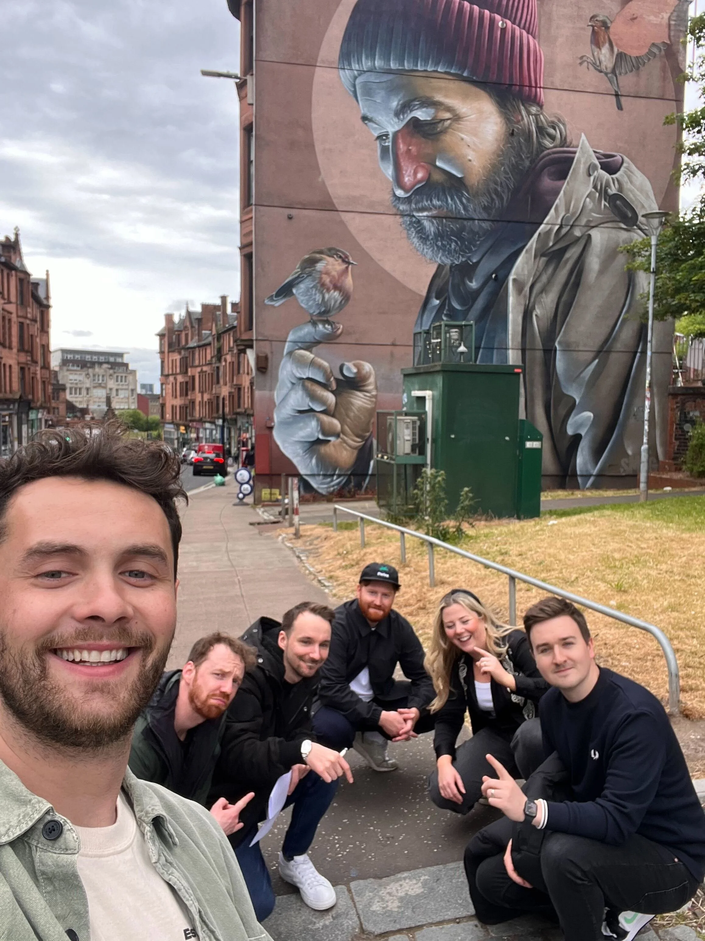 Group of people crouching in front of Glasgow Street Art.