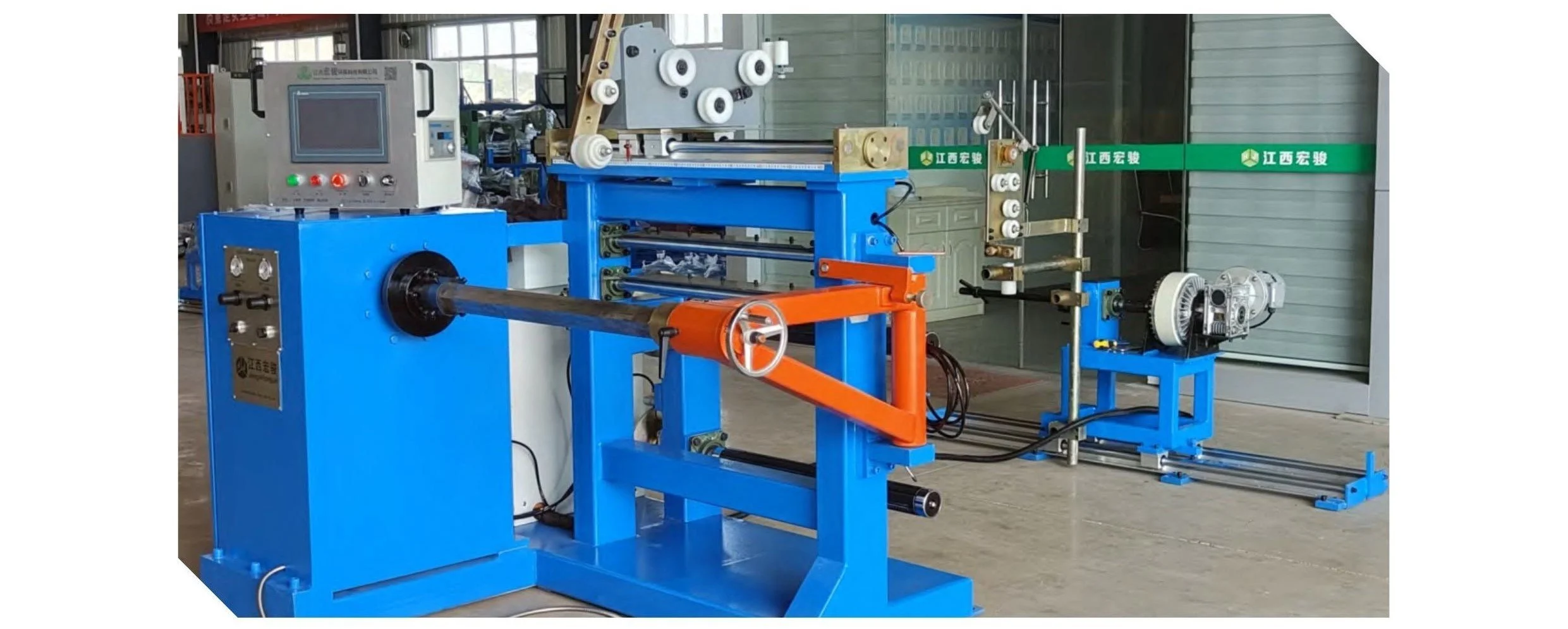 Industrial machinery in a factory with various colored components, including a large blue machine, a control panel, and equipment for manufacturing or testing.