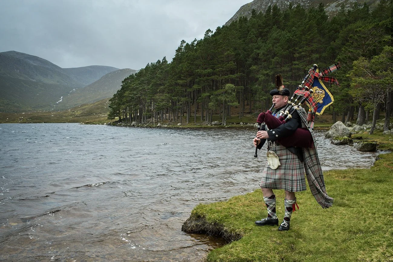 The Queen's Piper, Pipe Major Scott Methven, on the shores of Loch Muick on the Balmoral estate. He wears a kilt of Balmoral Tartan