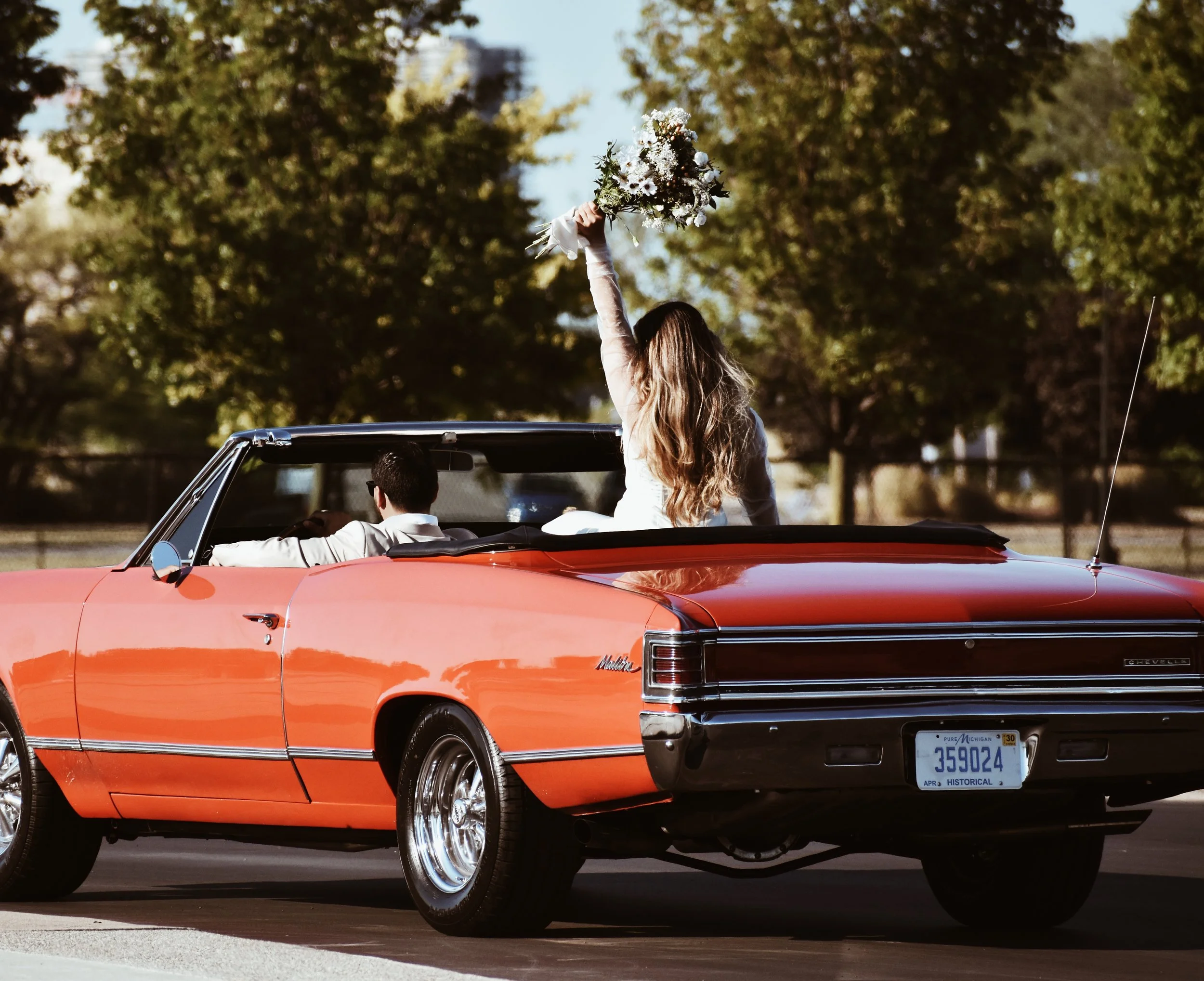 A bride holding her bouquet while sitting in a vintage red convertible. Cinematic wedding filmmaking that blends nostalgic storytelling with modern visuals to create emotional wedding films for adventurous couples in New Jersey.
