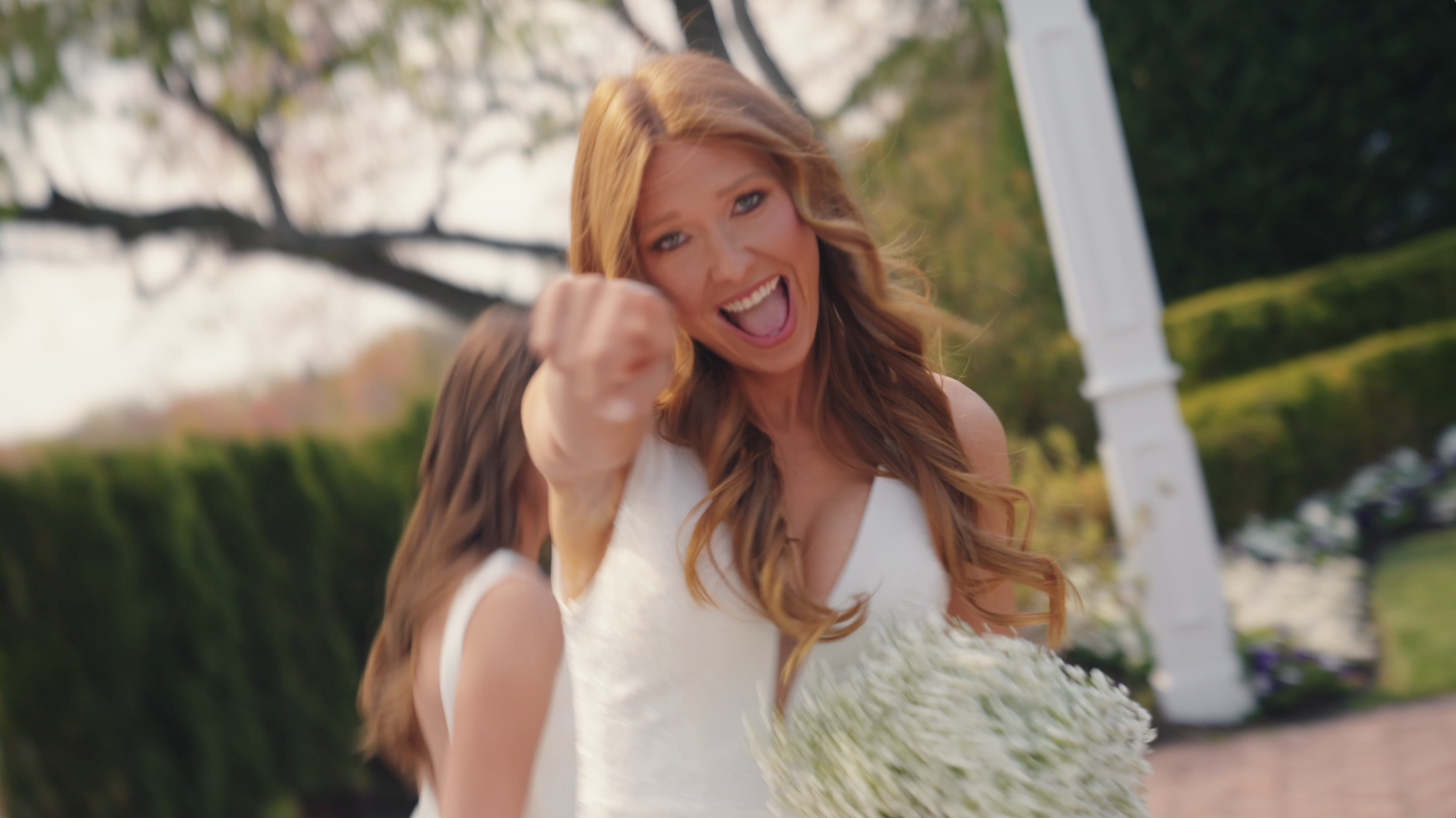 A wedding guest laughing and pointing toward the camera during a celebration. Capturing the unscripted moments, personality, and energy that make every wedding unique through cinematic wedding videography.