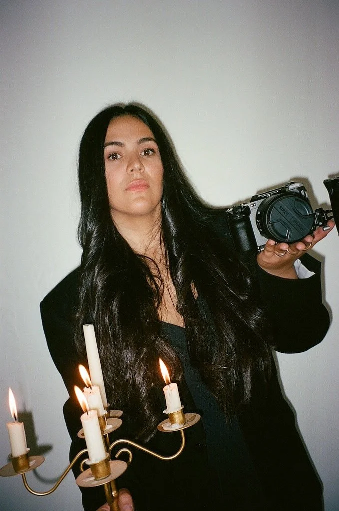 New Jersey wedding filmmaker Letty Rammal holding a camera and smiling. Founder of Letty Way Films, specializing in documentary wedding films, candid storytelling, vintage-inspired wedding videography, and destination weddings.