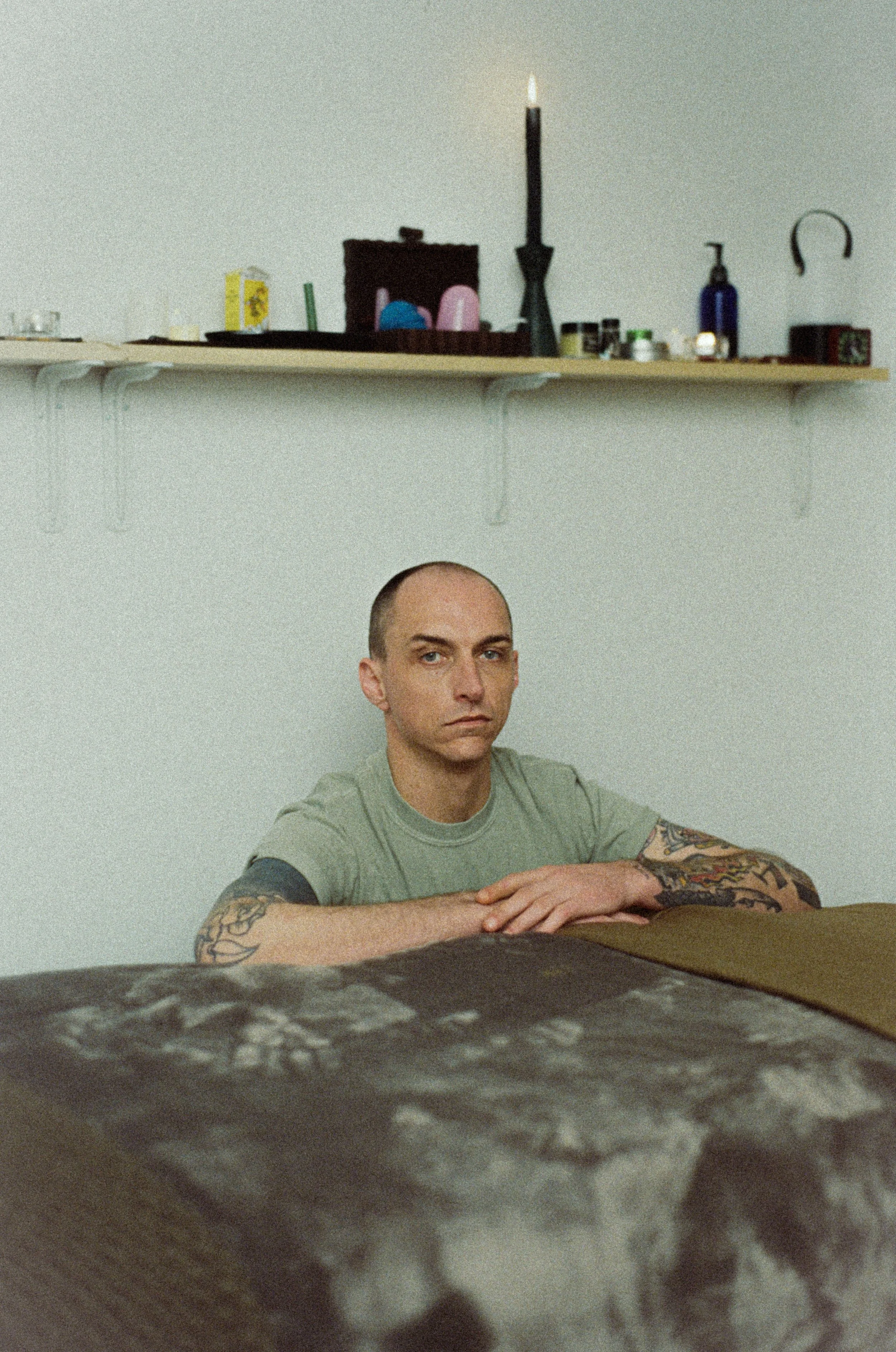 Portait photograph of Licensed Massage Therapist Tyler Keylon kneeling at a massage table in his studio. Photograph by Kyra Kilfeather of Second Sight Film.