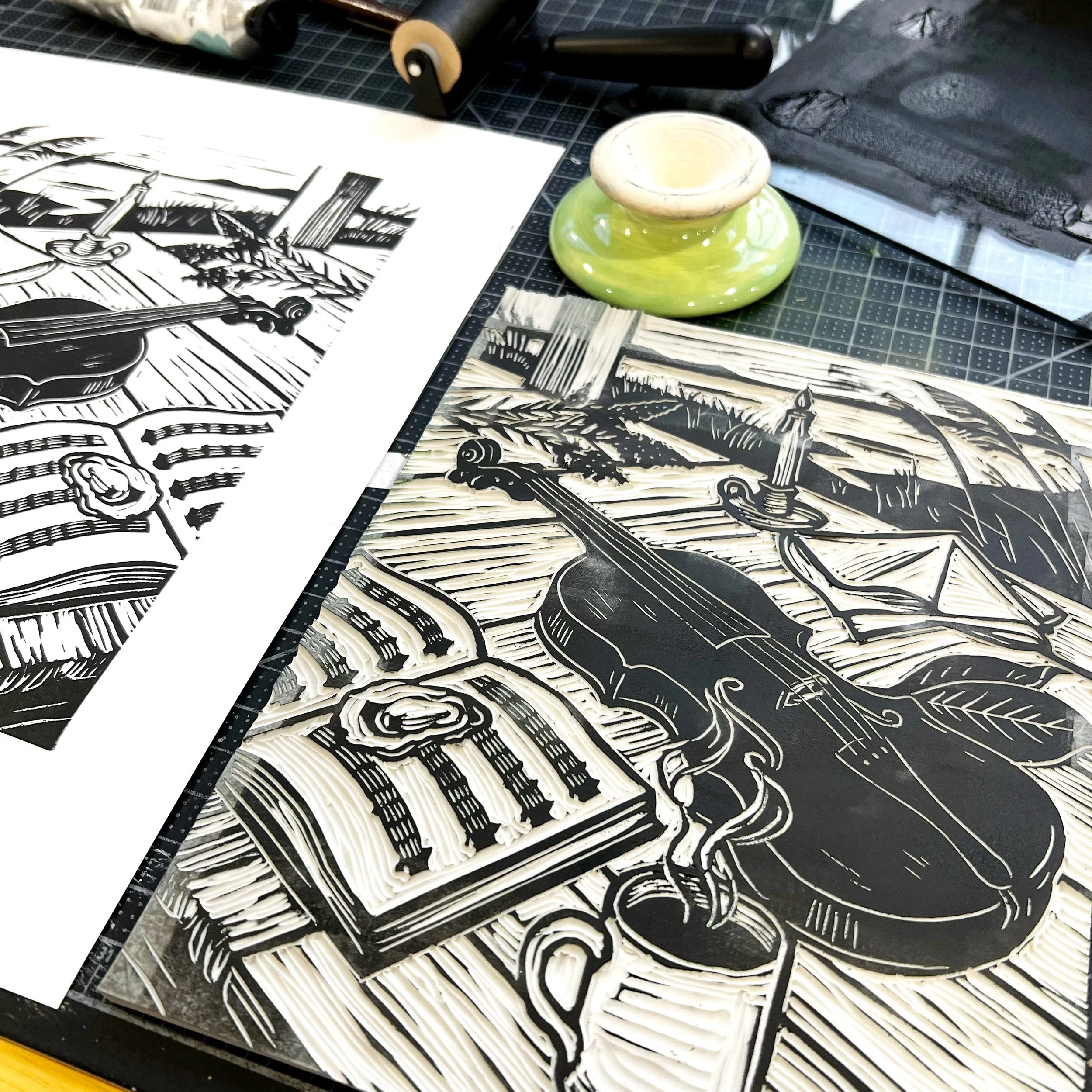 Close-up of carved linoleum blocks, a hand-pulled relief print, and printmaking tools on an artist's workbench.