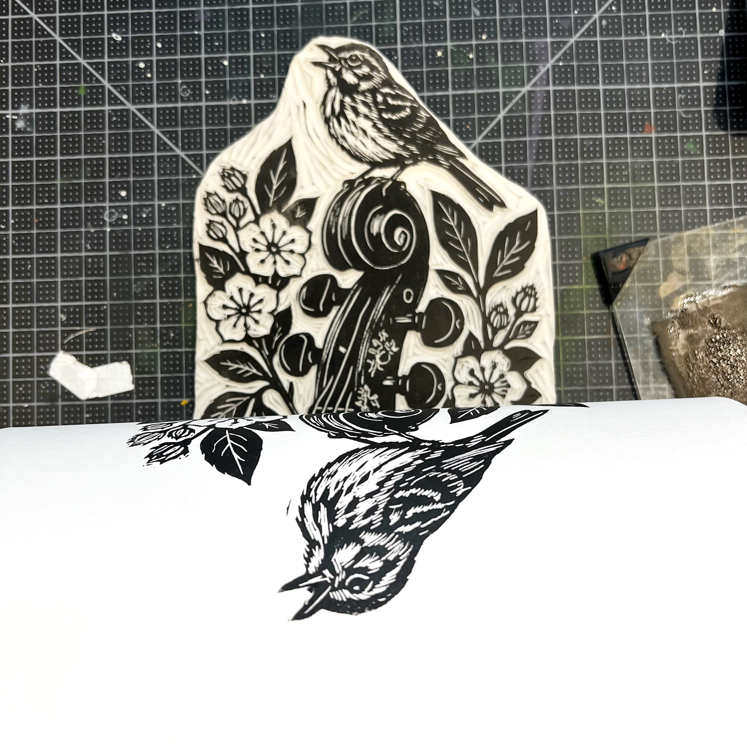 Hand-carved linoleum block featuring a song sparrow perched on a violin scroll with dogwood florals.