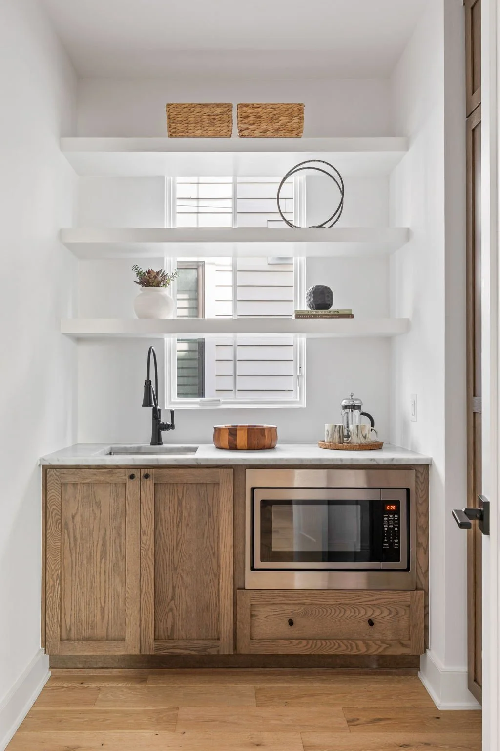Indianapolis Bright kitchen nook with wood cabinetry, marble countertop, open shelving, and window bringing in natural light