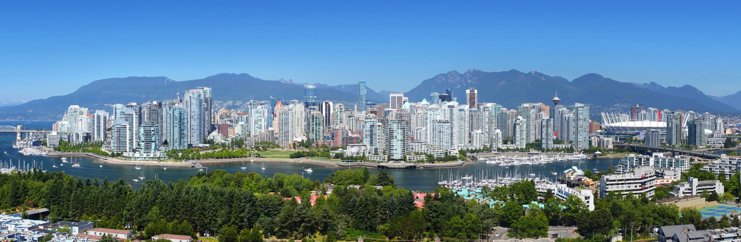 A panoramic view of the Vancouver skyline with the harbor in the foreground.