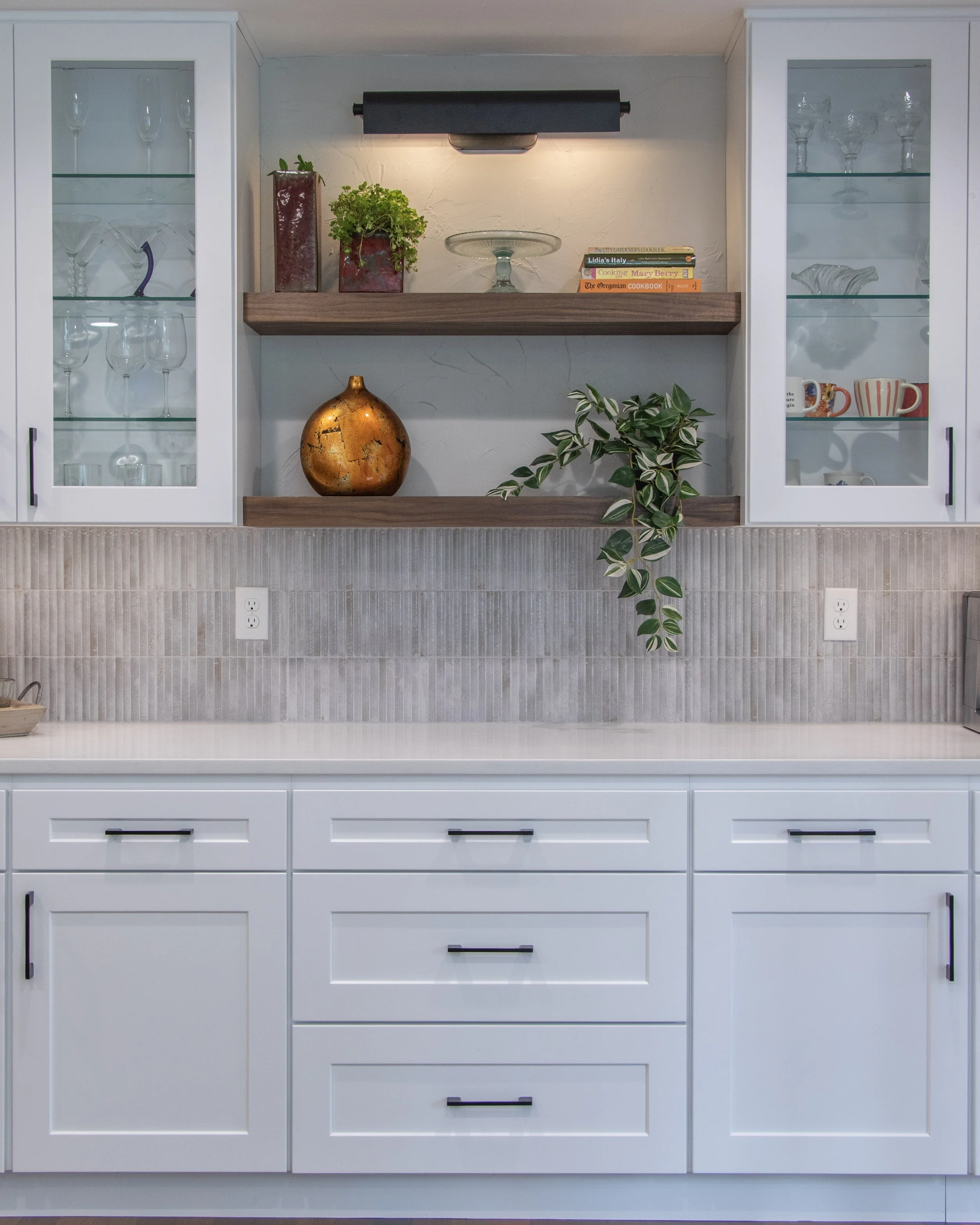 Remodeled buffet counter in a Vancouver kitchen with which upper and lower cabinets, and open walnut shelving between the upper cabinets. White quartz counters with a white/gray small vertical tile backsplash and glass cabinet front on upper cabinets