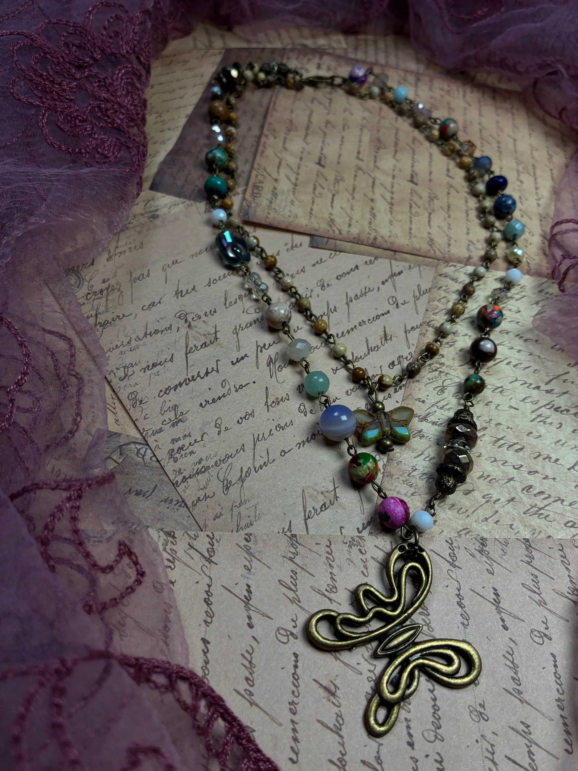 Close-up of the sculptural butterfly pendant and colorful natural-stone accents on Mariposa.