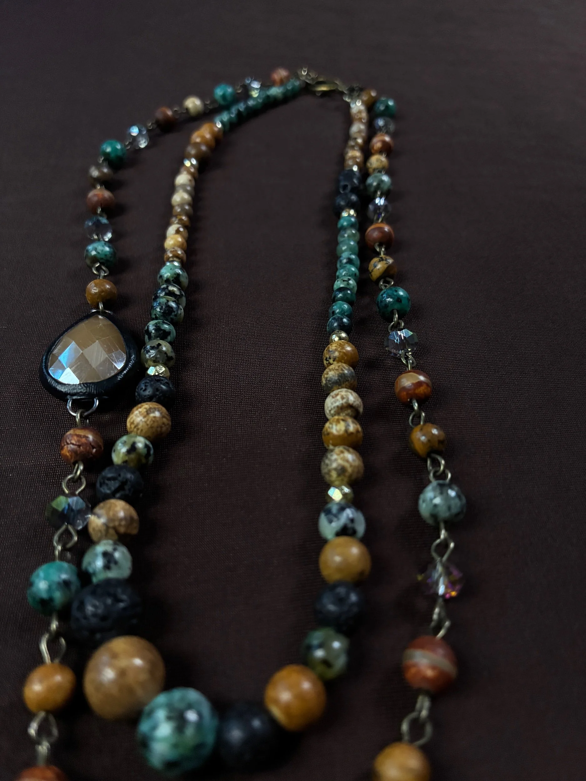 Close-up of the weathered heart pendant and earthy green beadwork on Moss Cathedral.