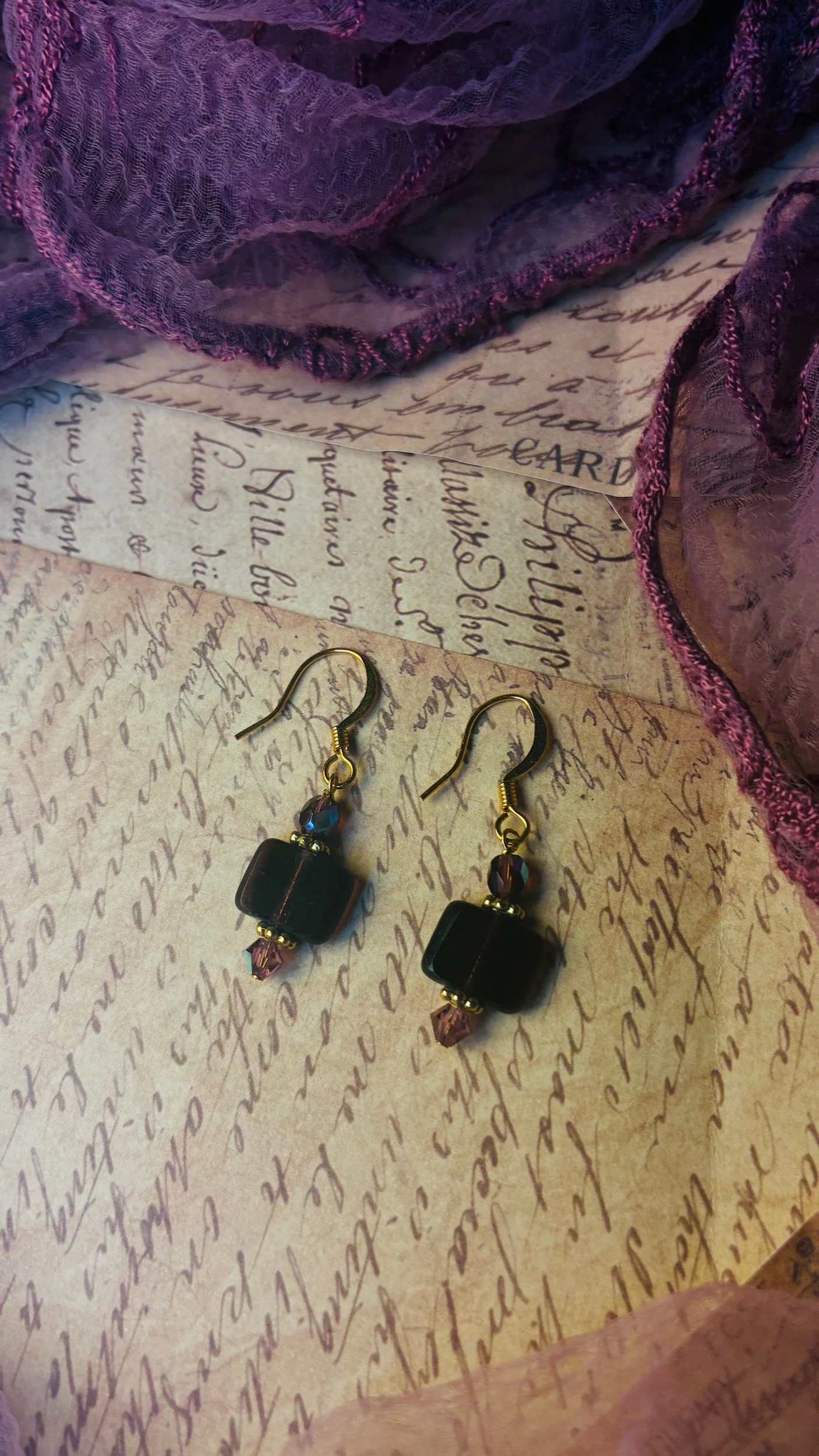 Close-up of the purple glass centerpiece and gold-tone details on the Plum earrings.