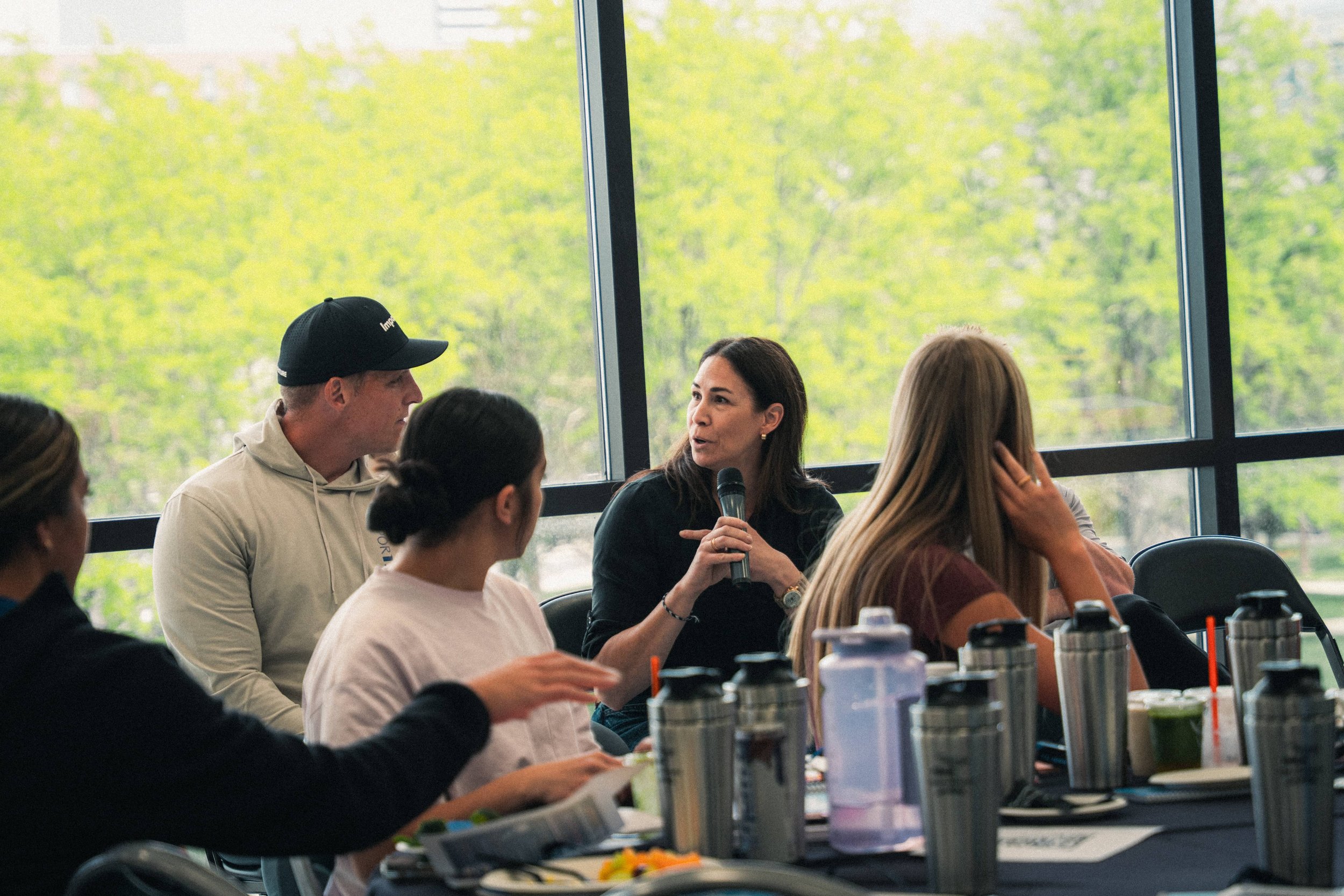 A woman speaking into a microphone, talking to other attendees at an event.