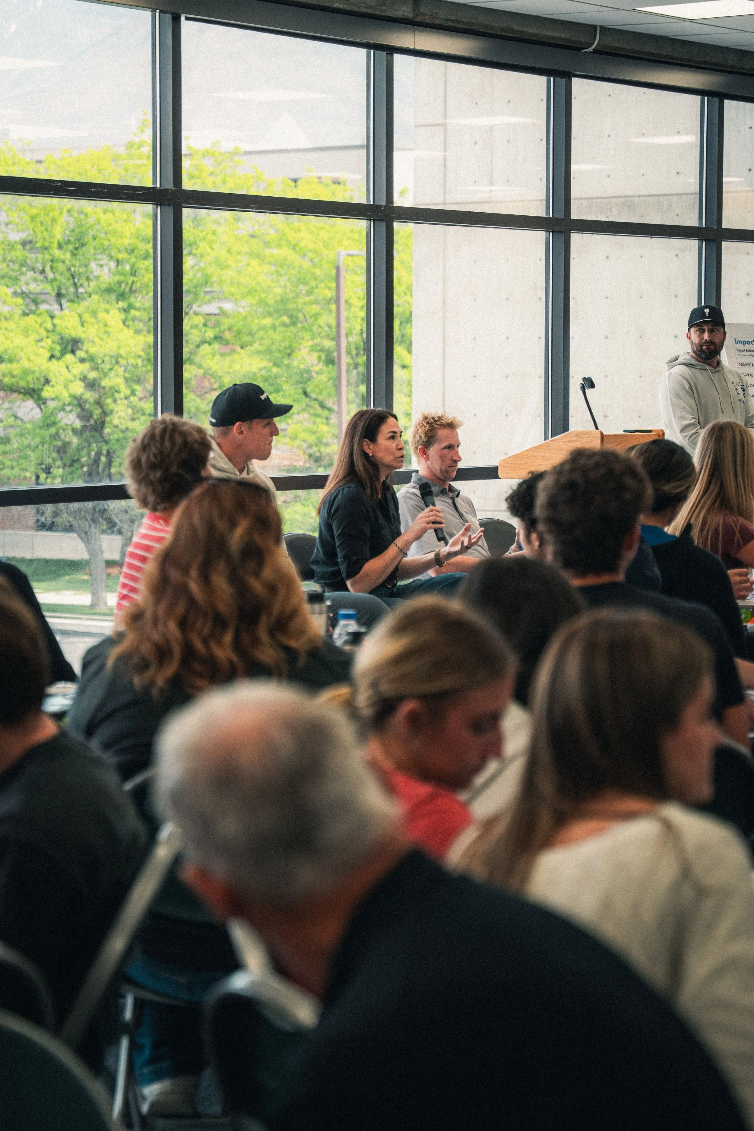 A woman speaking into a microphone at an event while surrounded by other attendees.