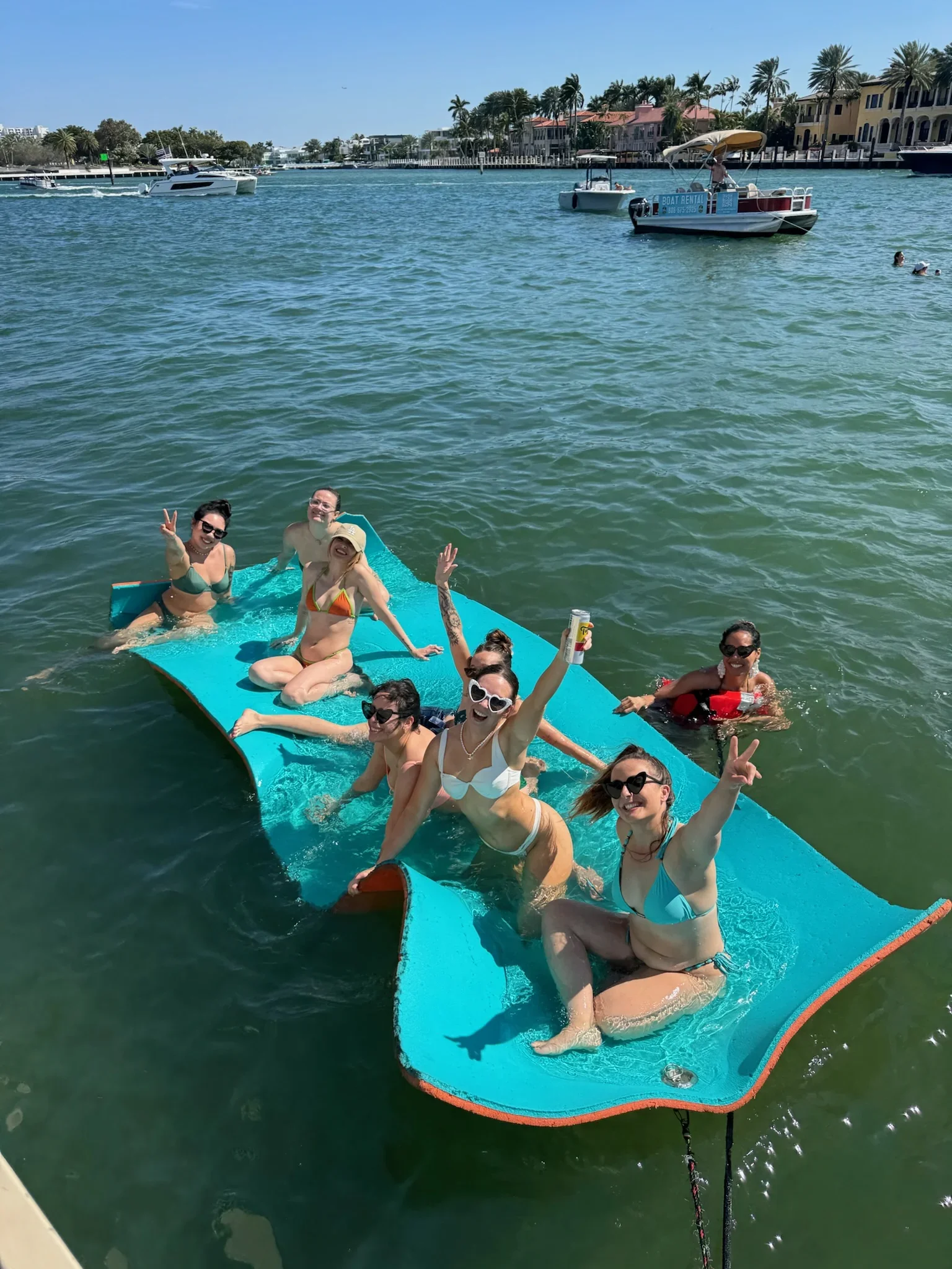 Group of bachelorettes on a the freaky tiki in a marina with boats and waterfront houses in the background.