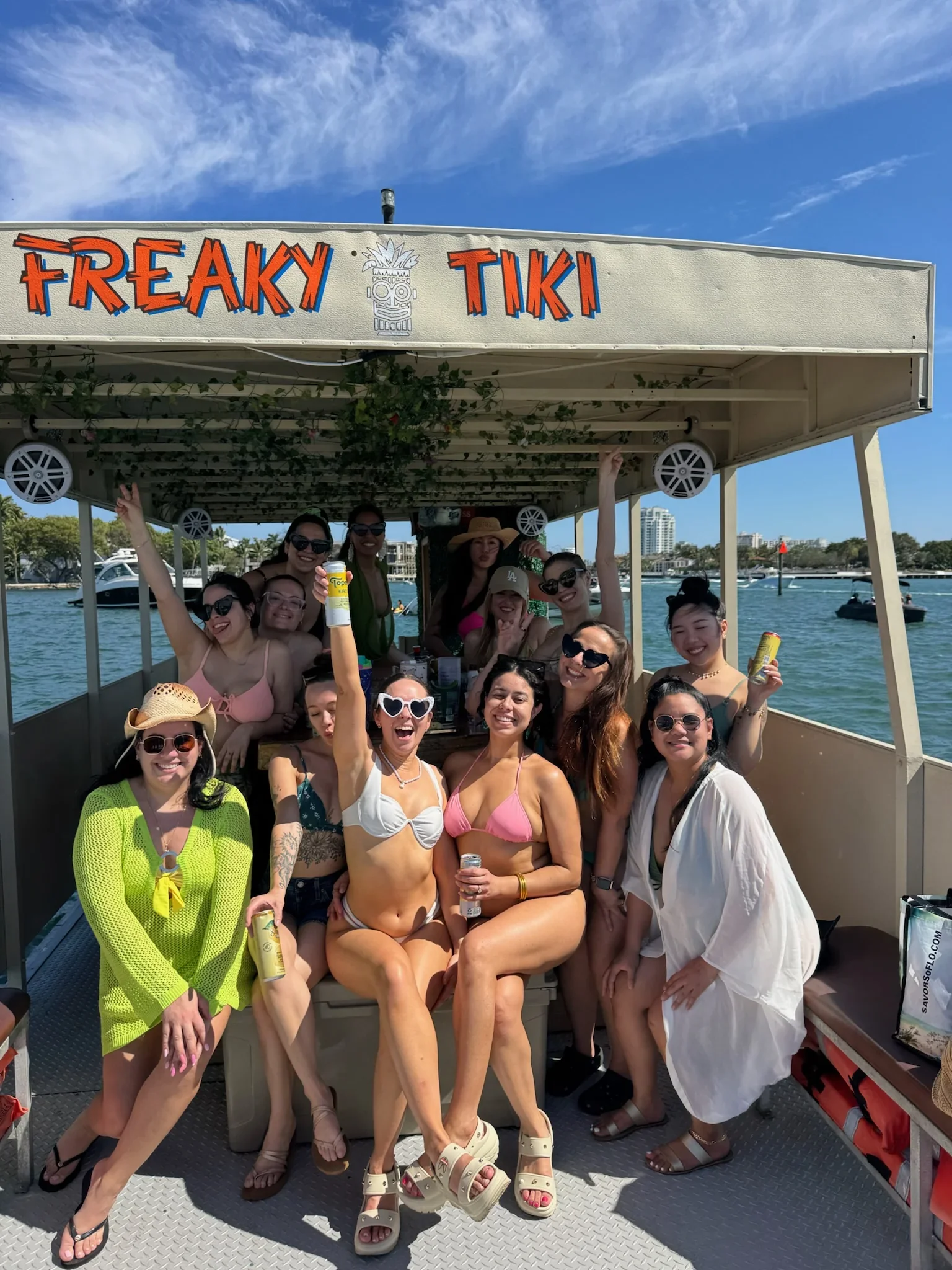 A group of bachelorettes on a boat with  Freaky Tiki Above them