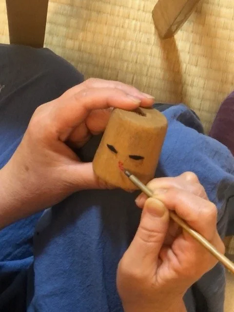 Hand-painted face of 31 "the Kokeshi Dolls* of  Factory Girls”*: "31" is the number of female factory workers who were unable to escape a fire at a local factory in 1900.