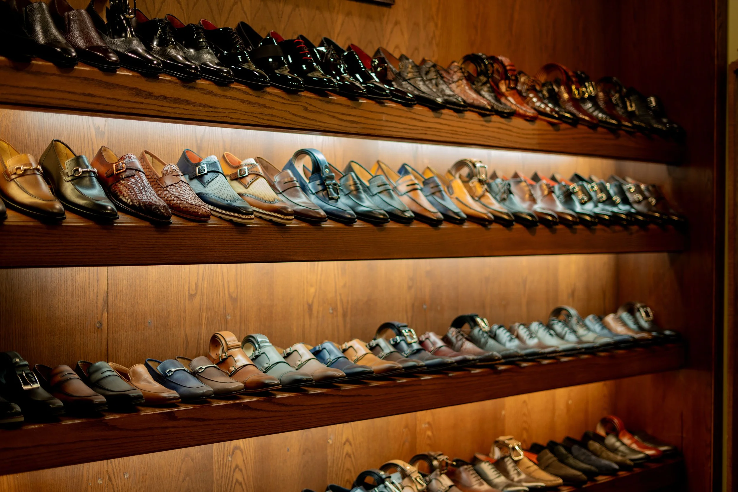 Multiple shelves of men's dress shoes arranged by style and color in a shoe store.